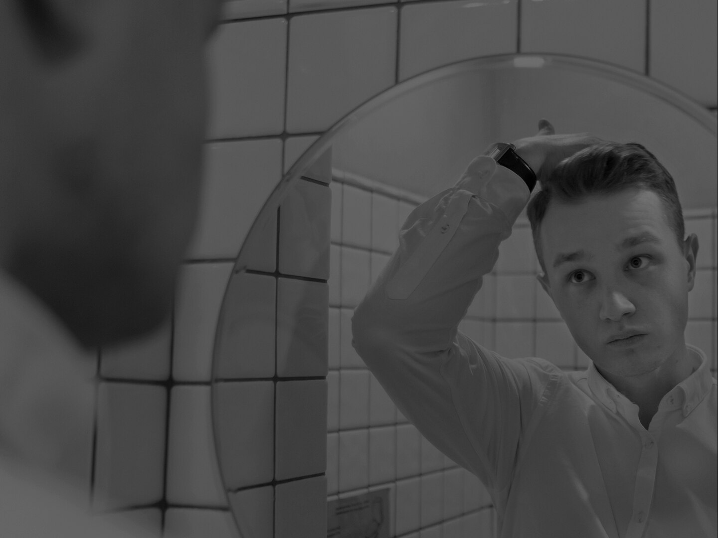 A guy wth freckles, running his hands through his hair.