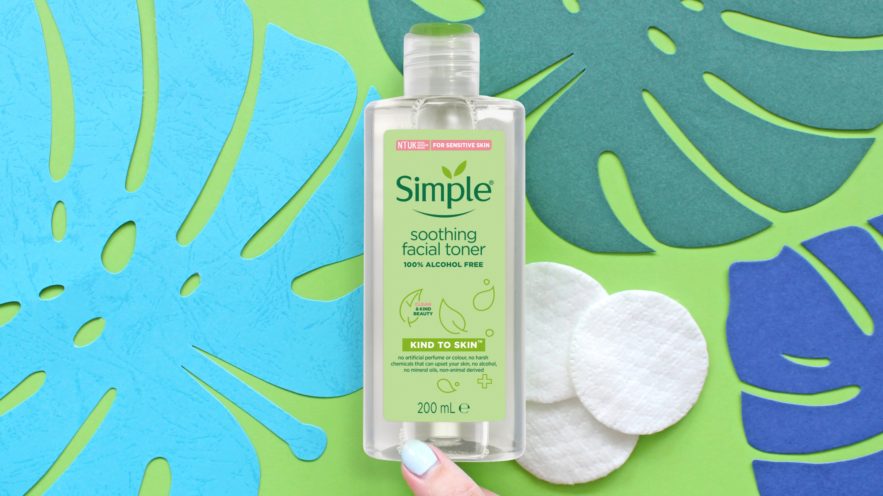 Chai Toner làm dịu da của Simple nằm trên cuốn tạp chí cùng một số bông trang điểm ở phần nền ảnh