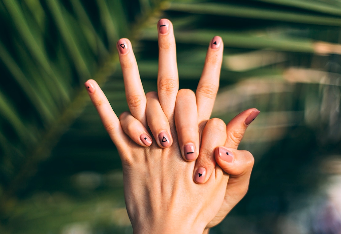 moisturized hands with pink nail polish and black designs