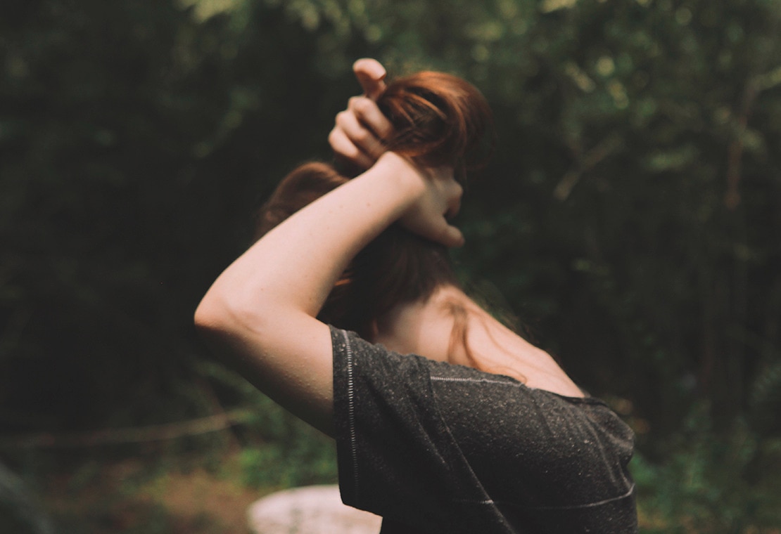 Woman with red hair pulling her hair up