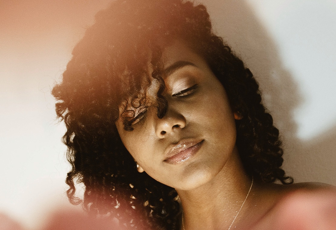 Woman with curly hair and sunshine on her face