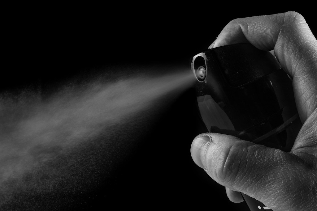 A guy spraying on antiperspirant