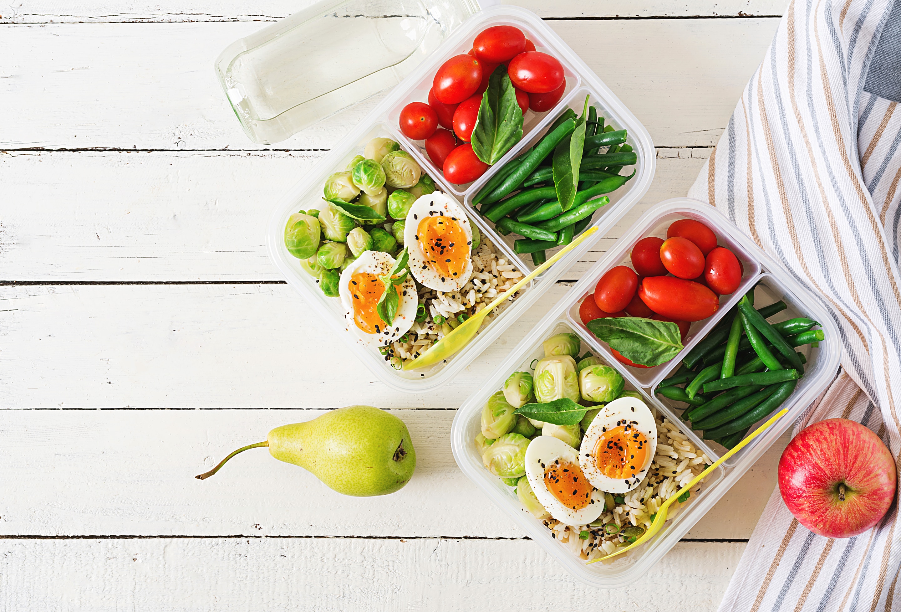 beans, plum tomatoes, sprouts and boiled eggs in a lunch box with pear and apple on the side