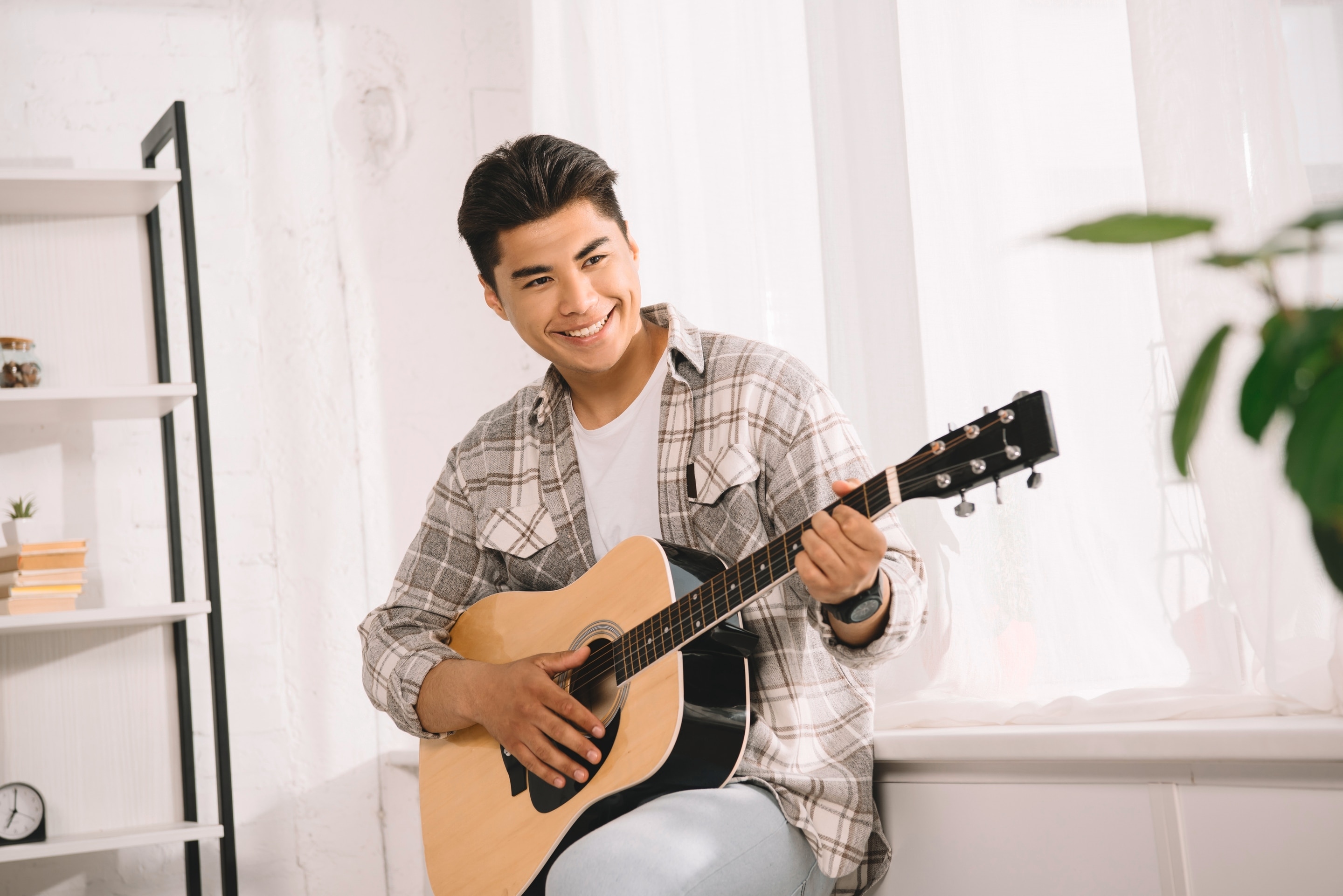 Asian man playing the guitar.