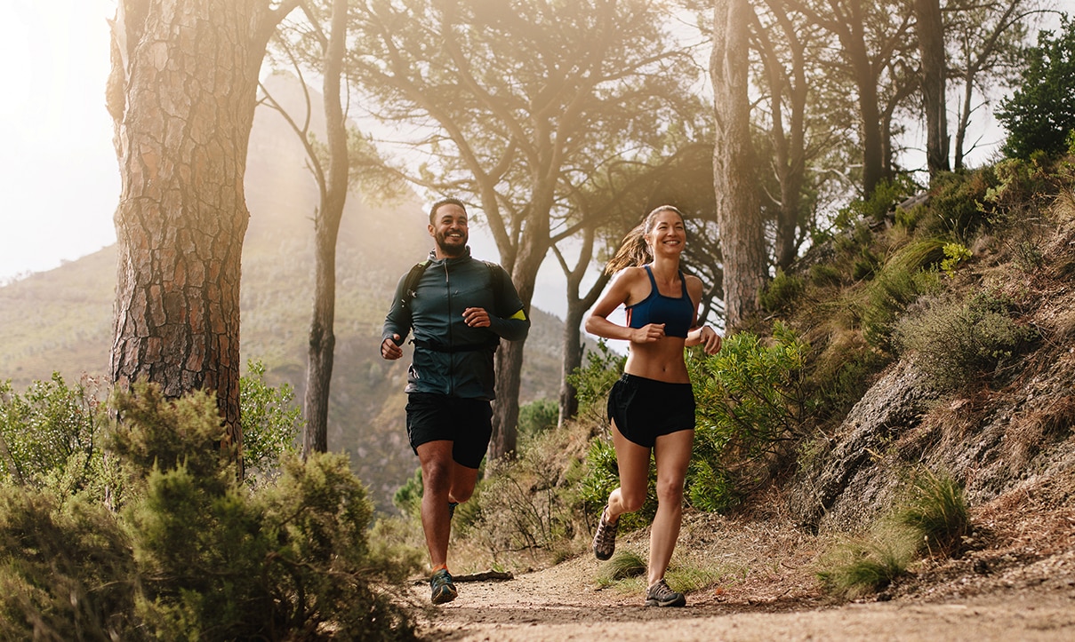 Couple jogging on a forest trail.