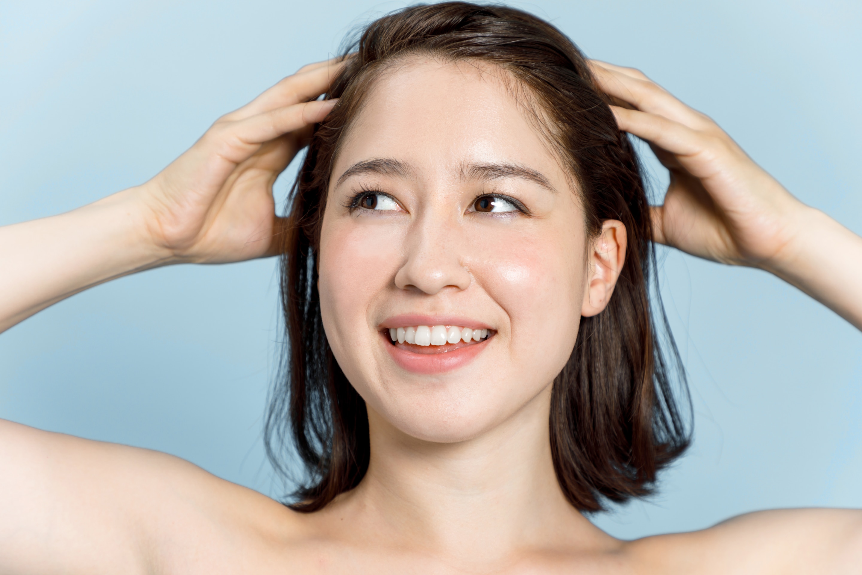 gội đầu dưỡng sinh kỹ thuật massage da đầu cô gái chạm hai bàn tay lên đầu trên nền xanh dương