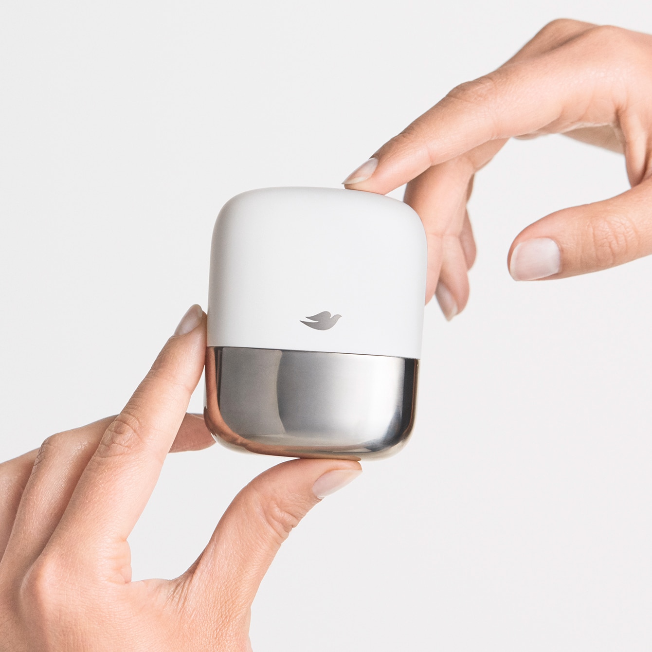 Hands holding the stainless steel Dove refillable deodorant case