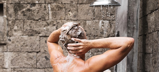 Homem no chuveiro lavando o cabelo