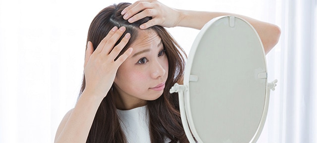 Mulher inspecionando couro cabelo no espelho