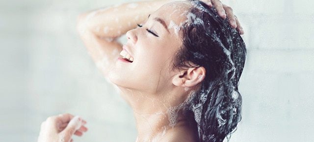 Smiling woman in shower washing hair
