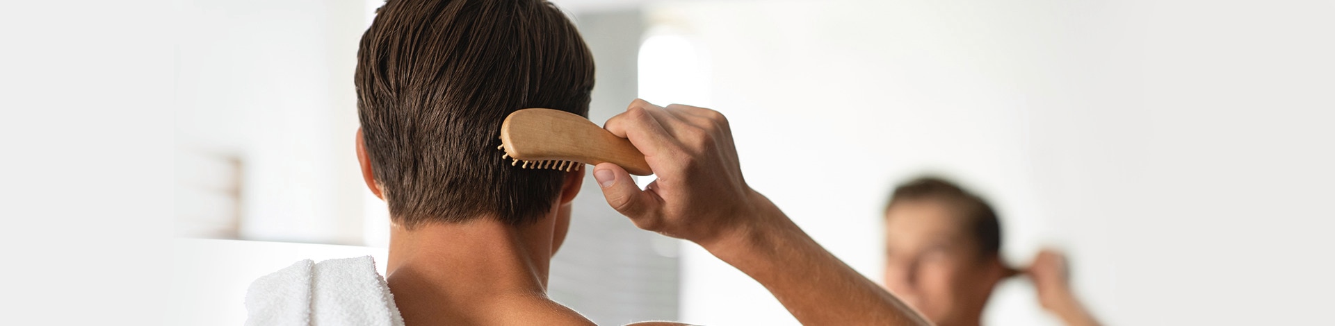 Man brushing hair while looking in the mirror
