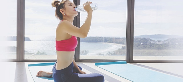 Mulher bebendo água durante treino de yoga