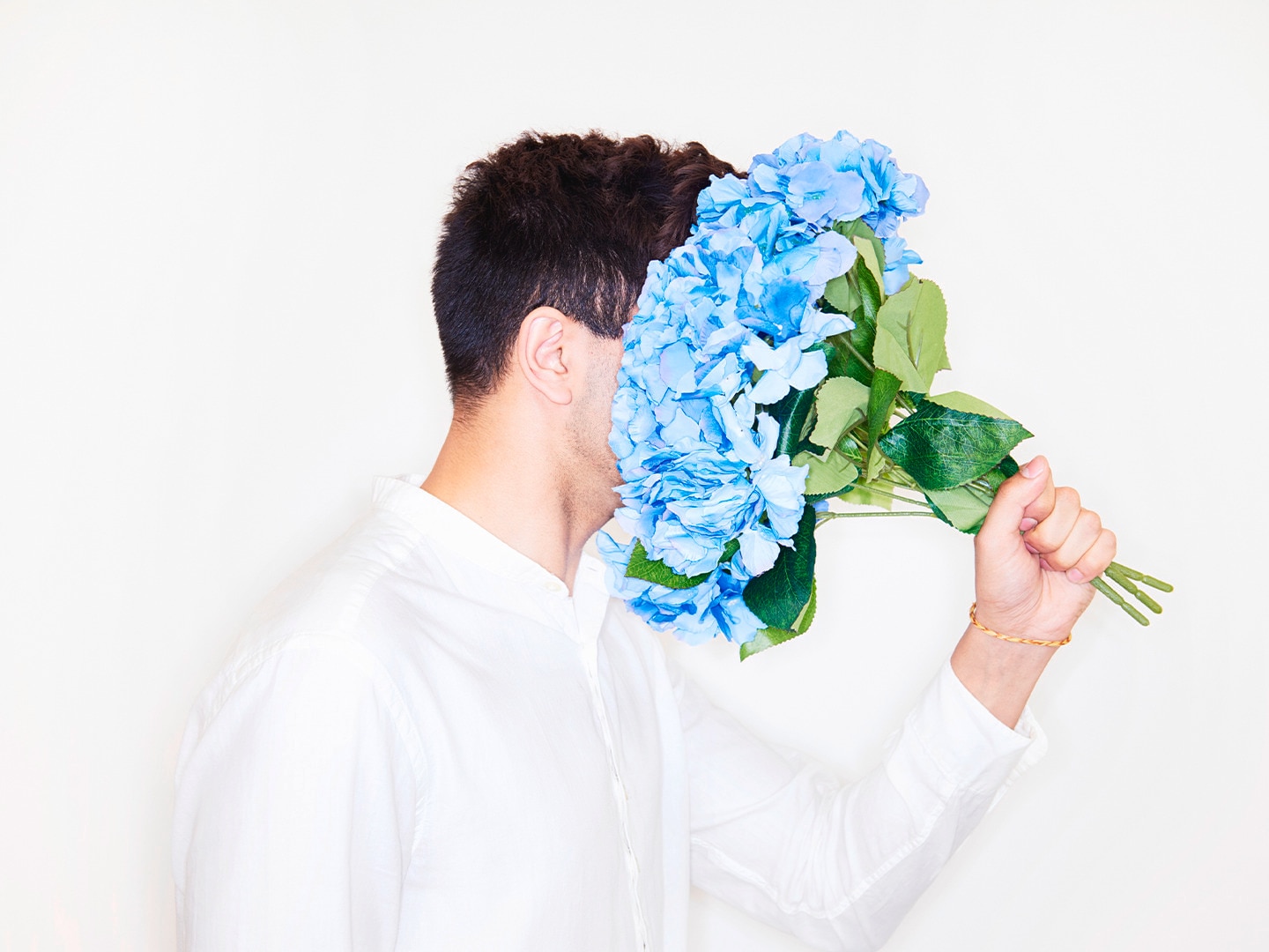 Guy with his head in a bouquet of blue flowers
