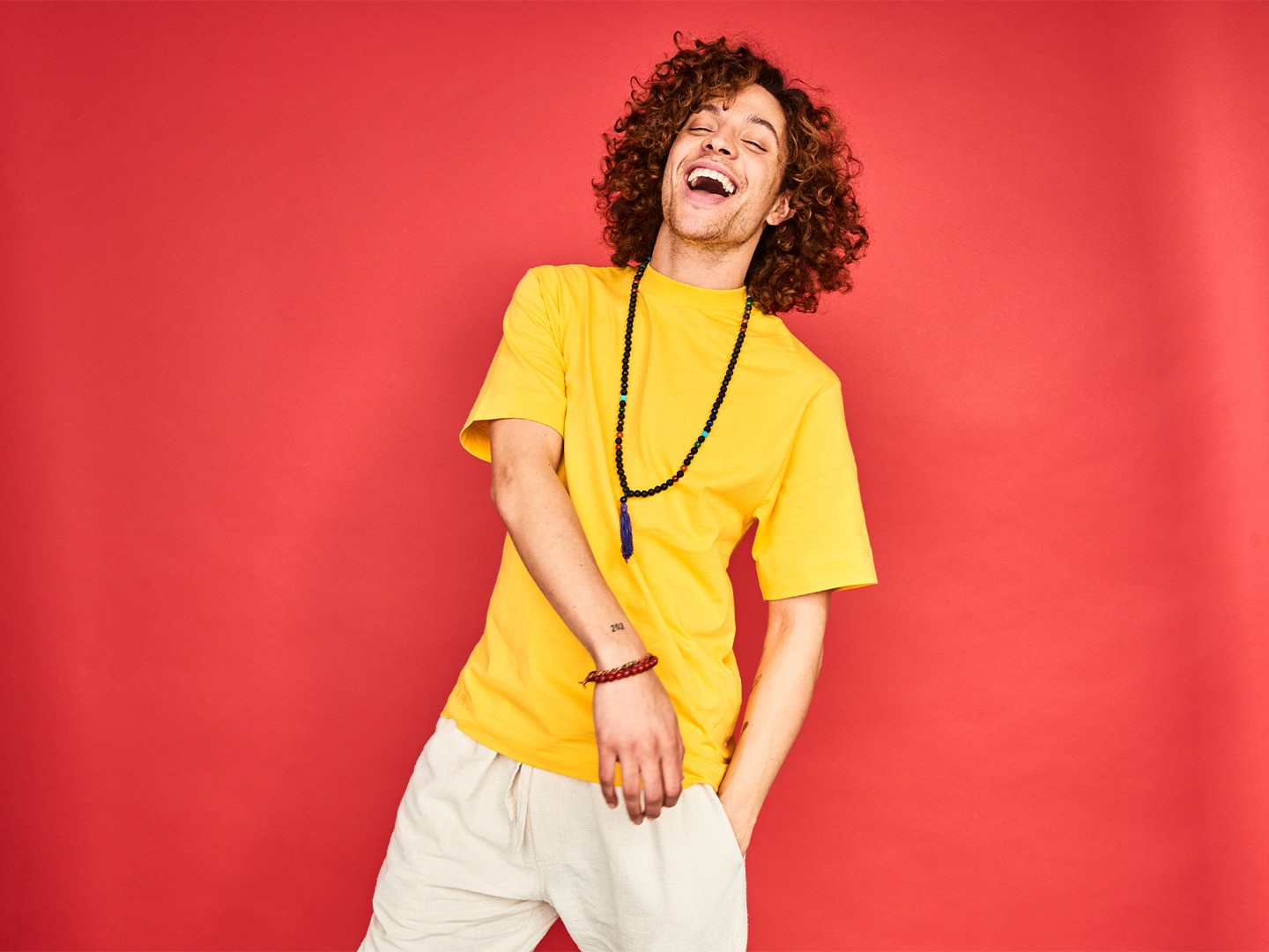 Guy in yellow tshirt laughing against red background