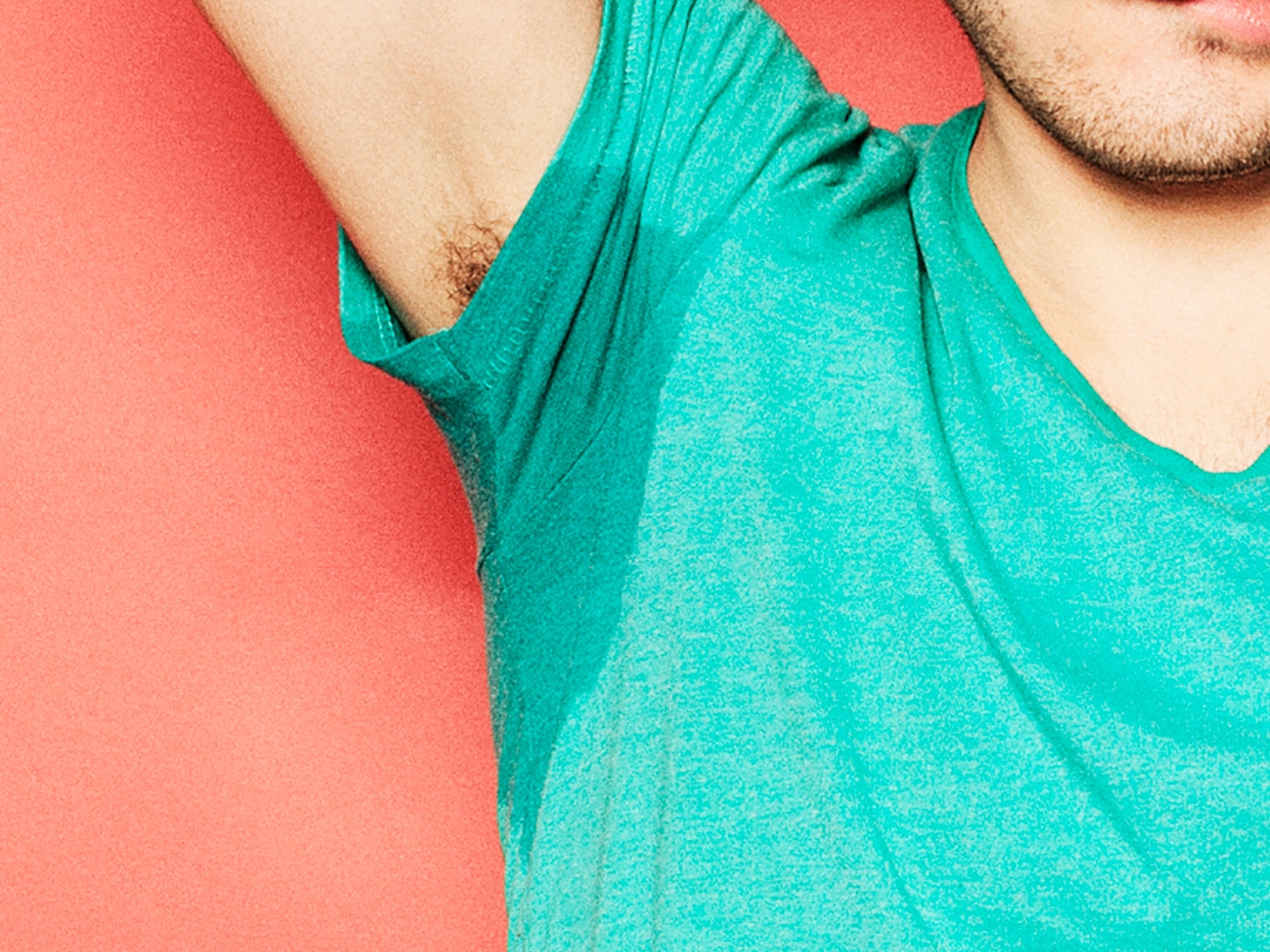 Guy holding up sweaty underarm in teal tshirt