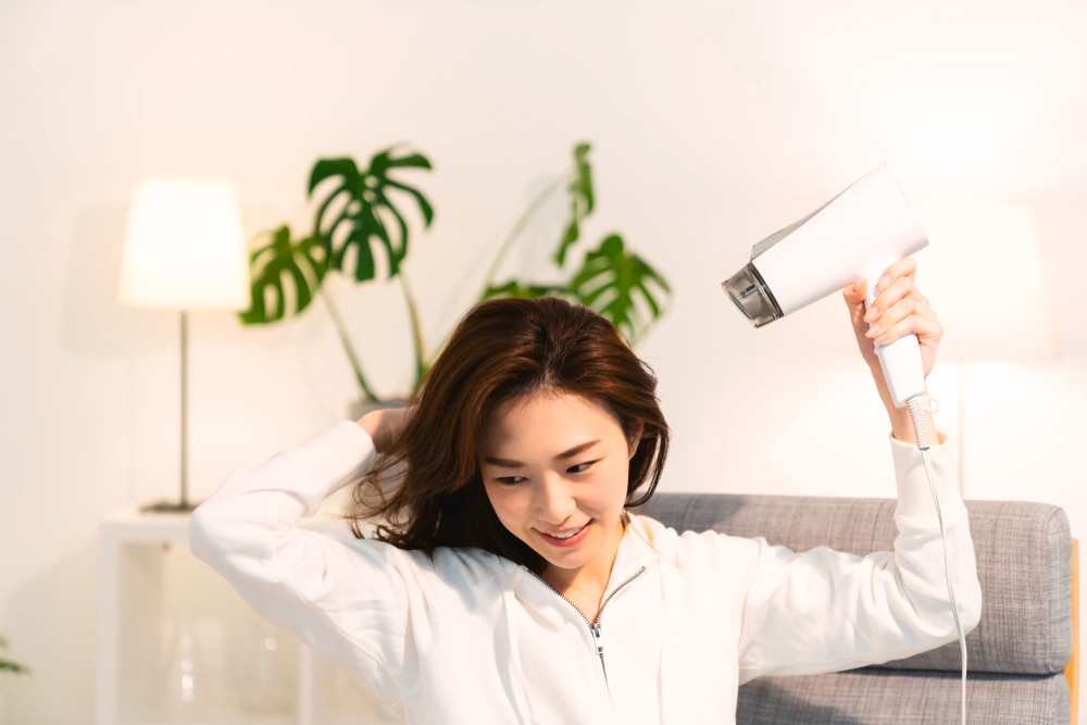 Asian girl blow drying her hair