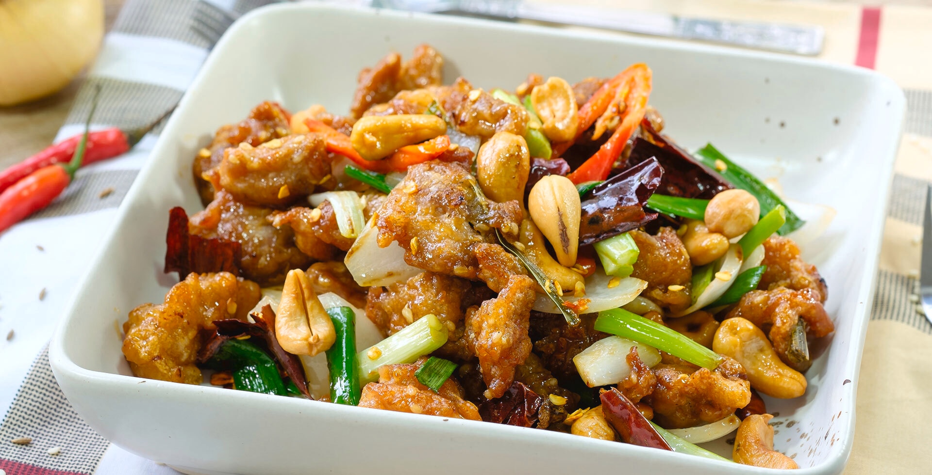 Ayam kung pao dalam mangkuk putih disajikan sebagai menu makan malam untuk keluarga