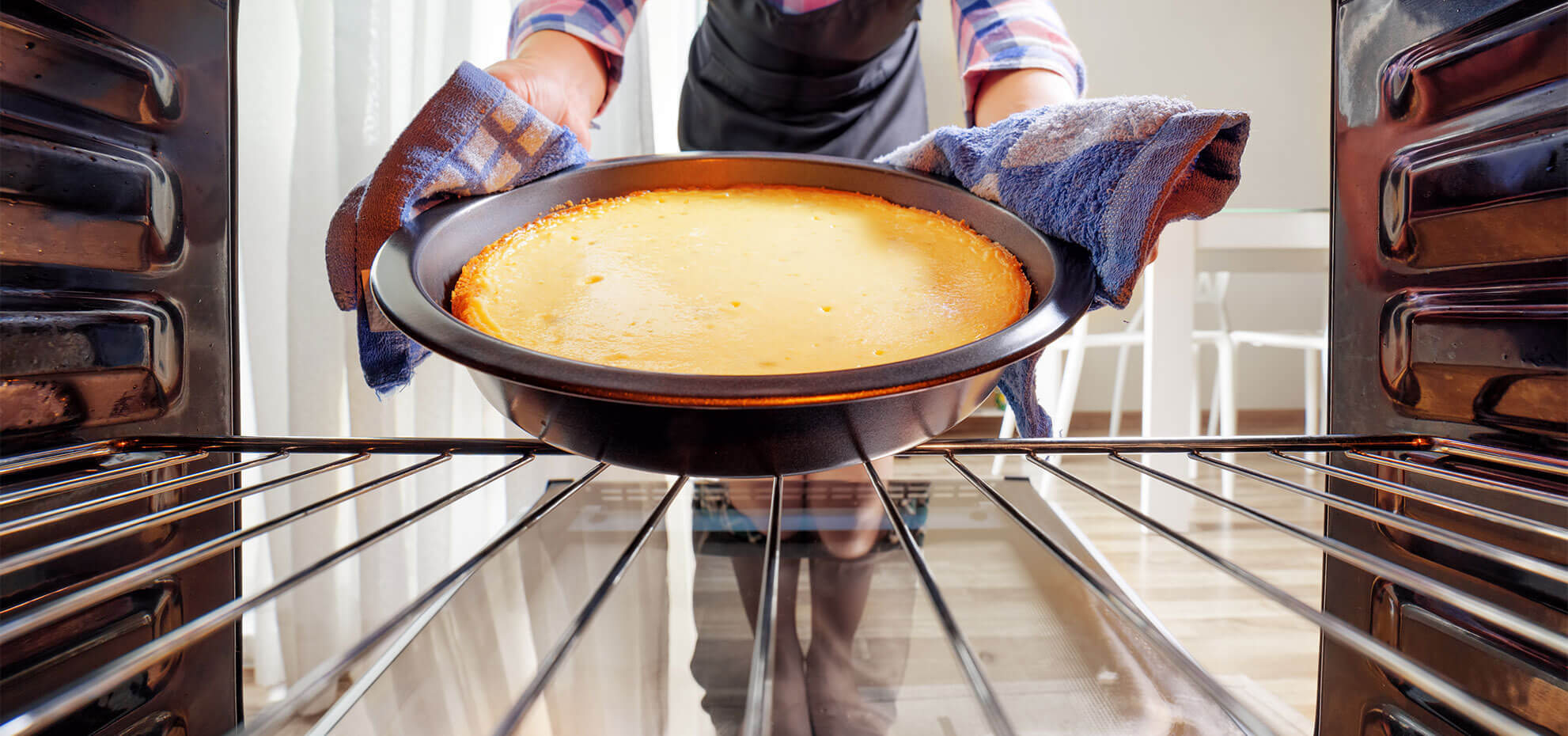 Seorang wanita tengah memasukkan adonan kue ke dalam oven