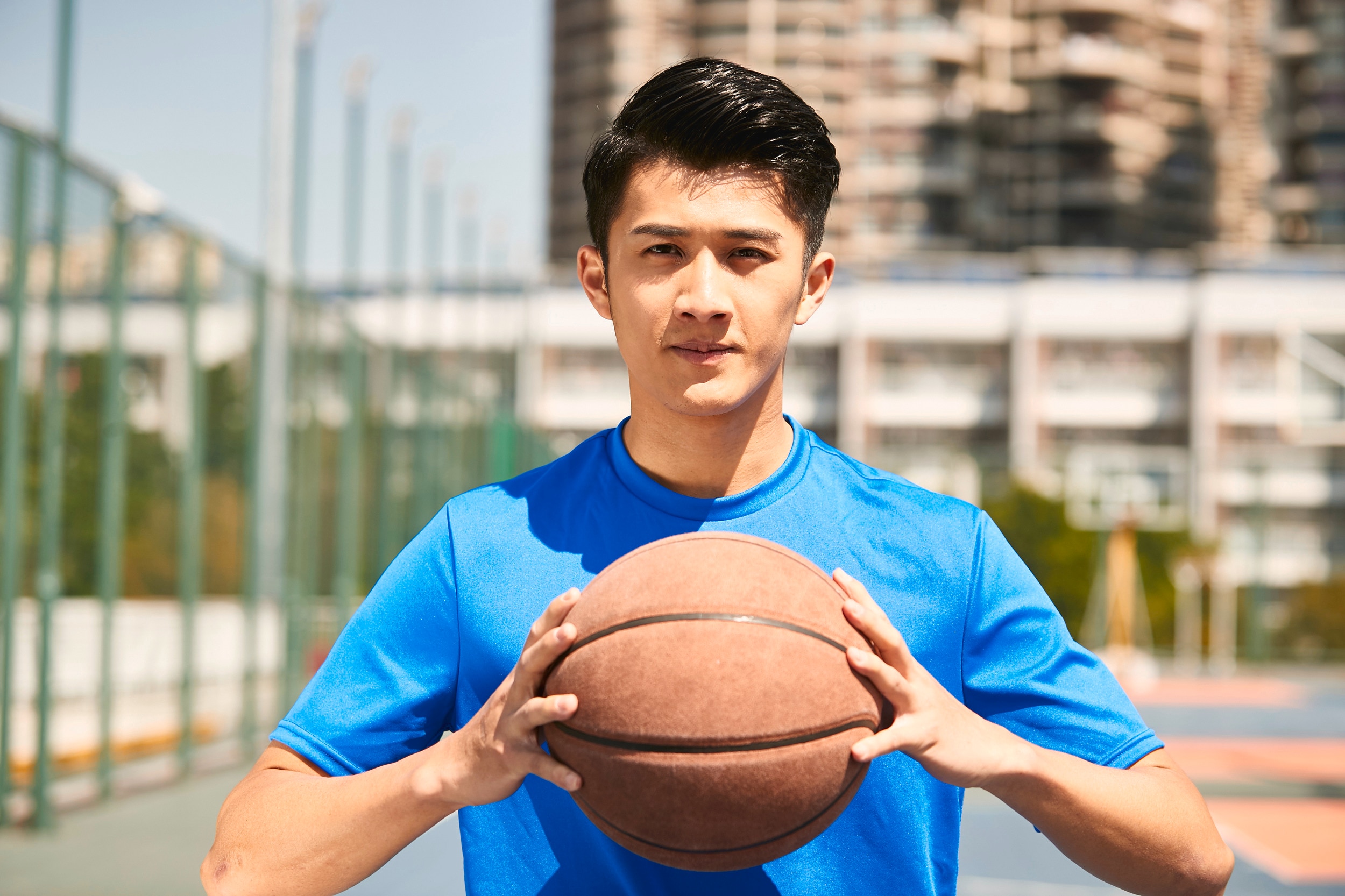 pria asia sedang bermain basket di luar ruangan