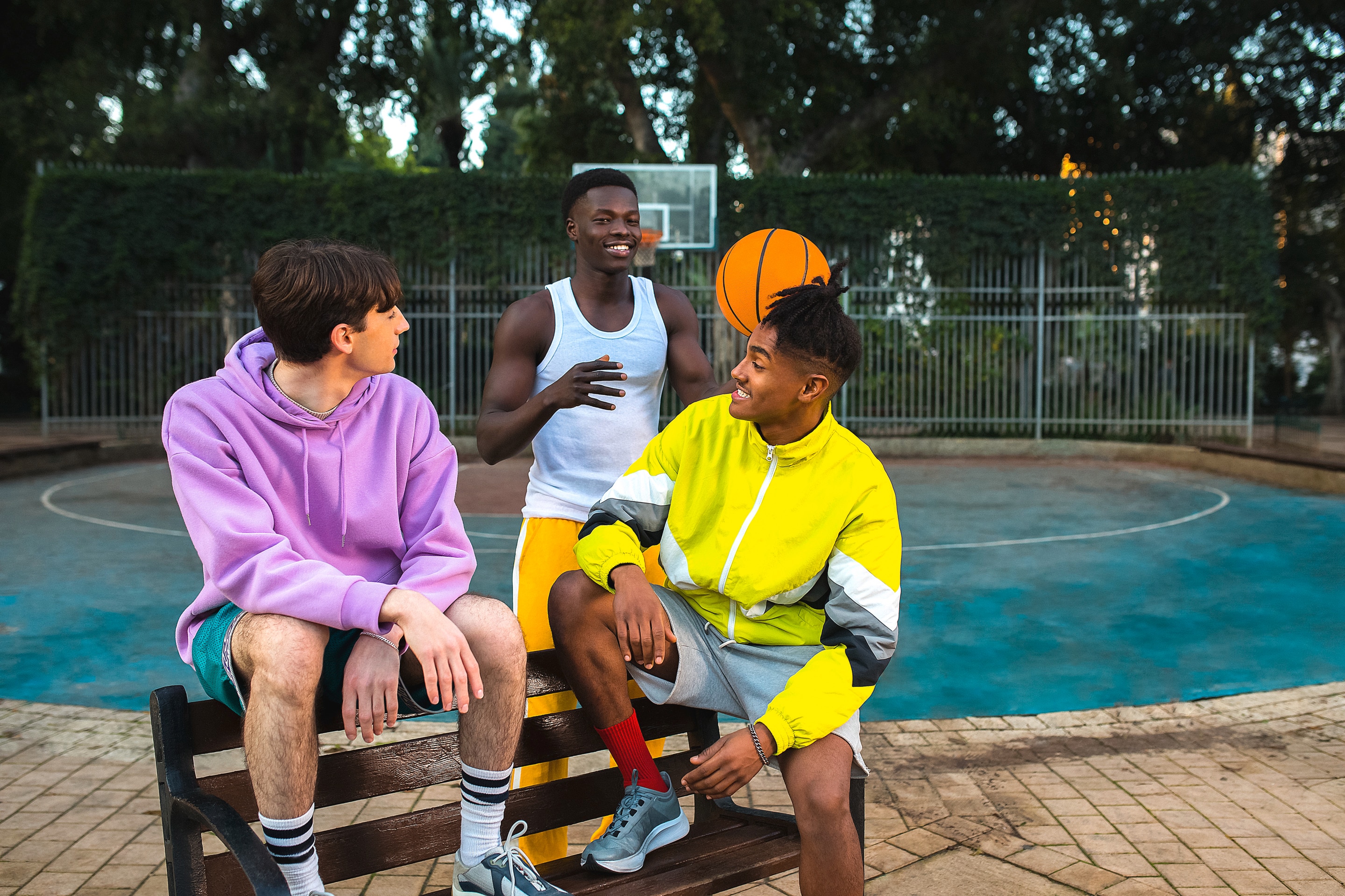 Three men sitting on a basketball court