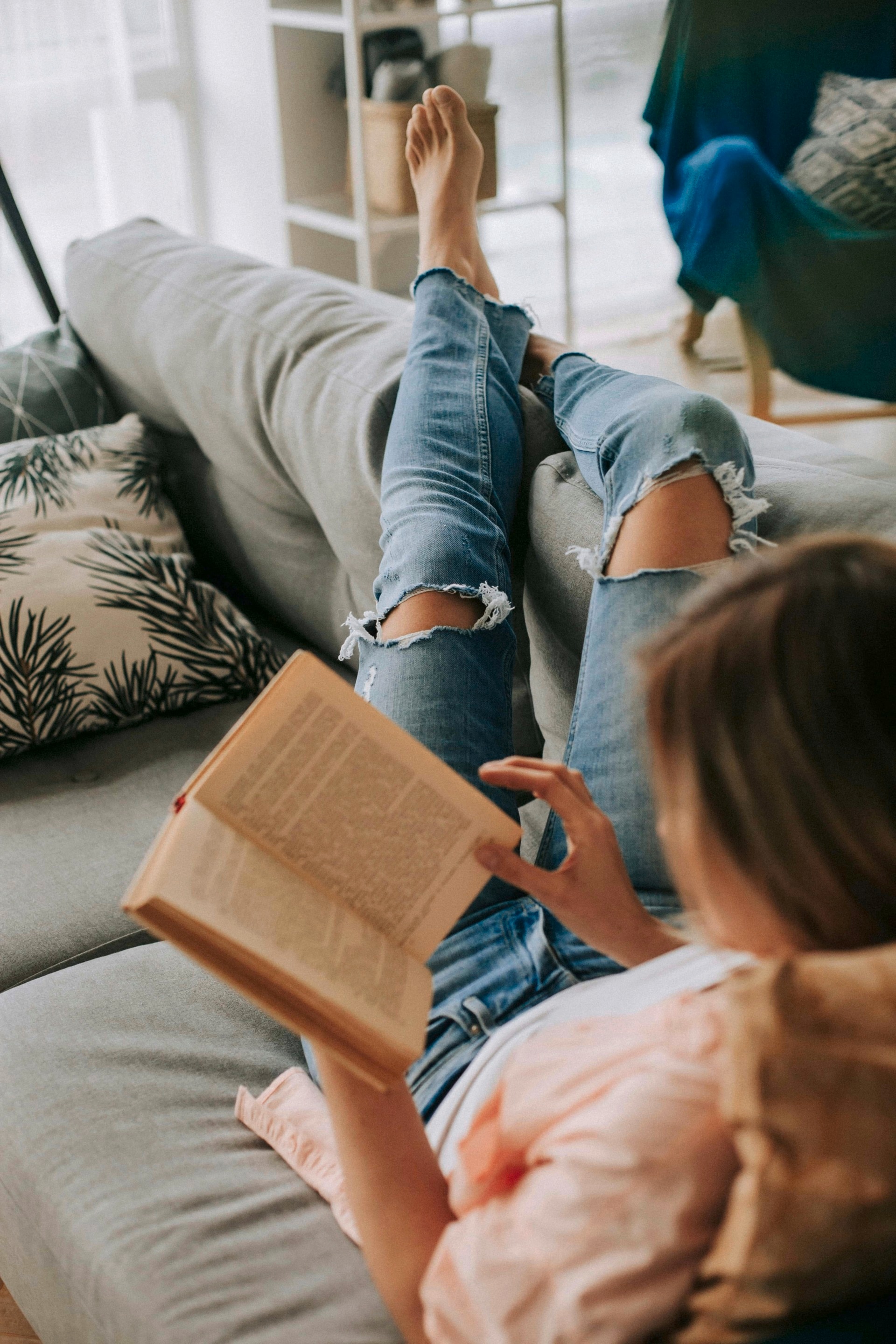 Uma mulher relaxa no sofá lendo um livro