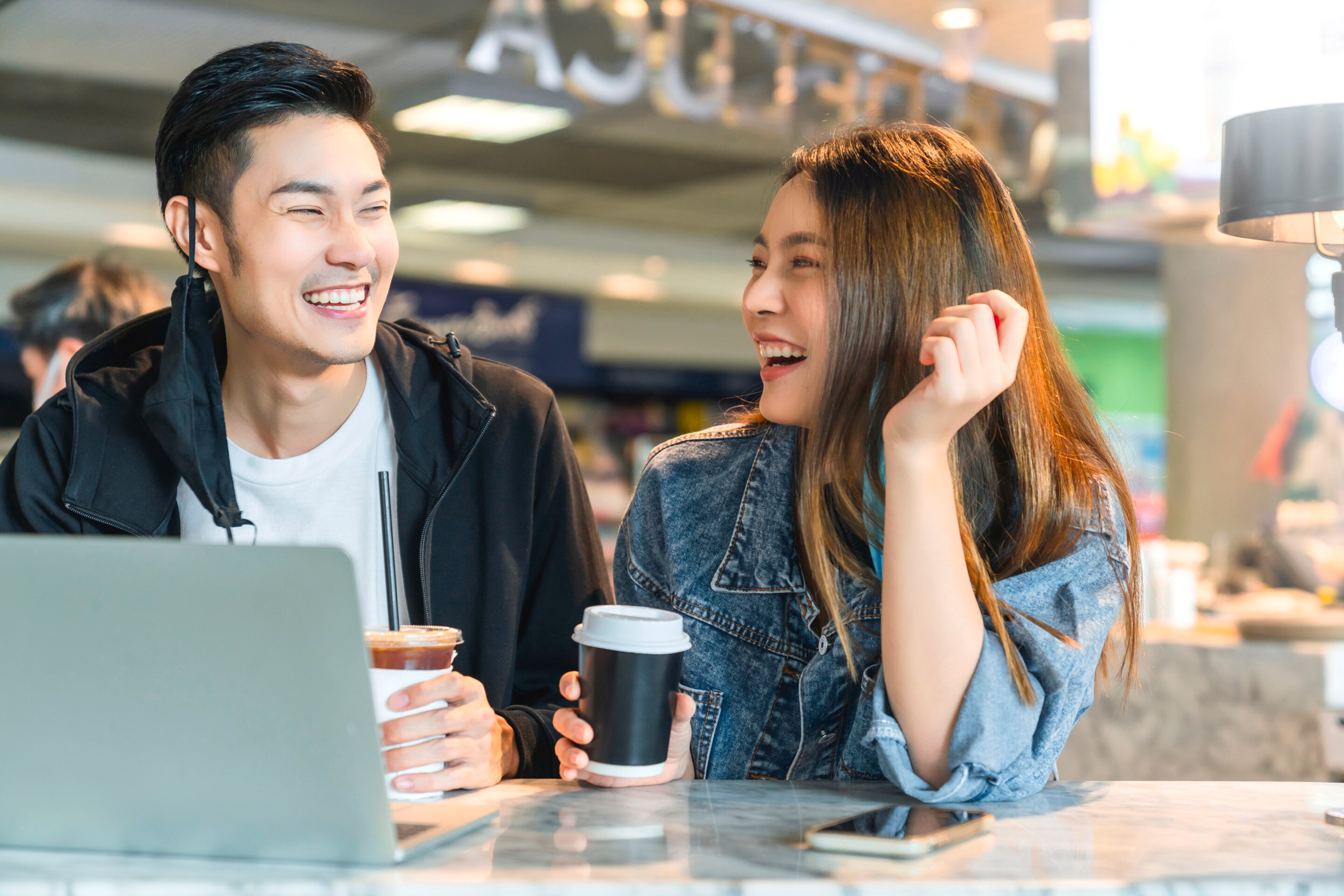 Happy Asian couple laughing over coffee