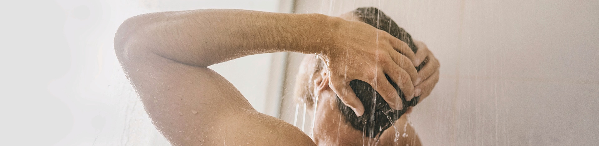 Homem no chuveiro condicionando o cabelo