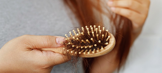Women checking hairbrush for hair loss Text