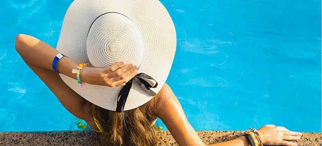 Mulher com chapéu de sol à beira da piscina