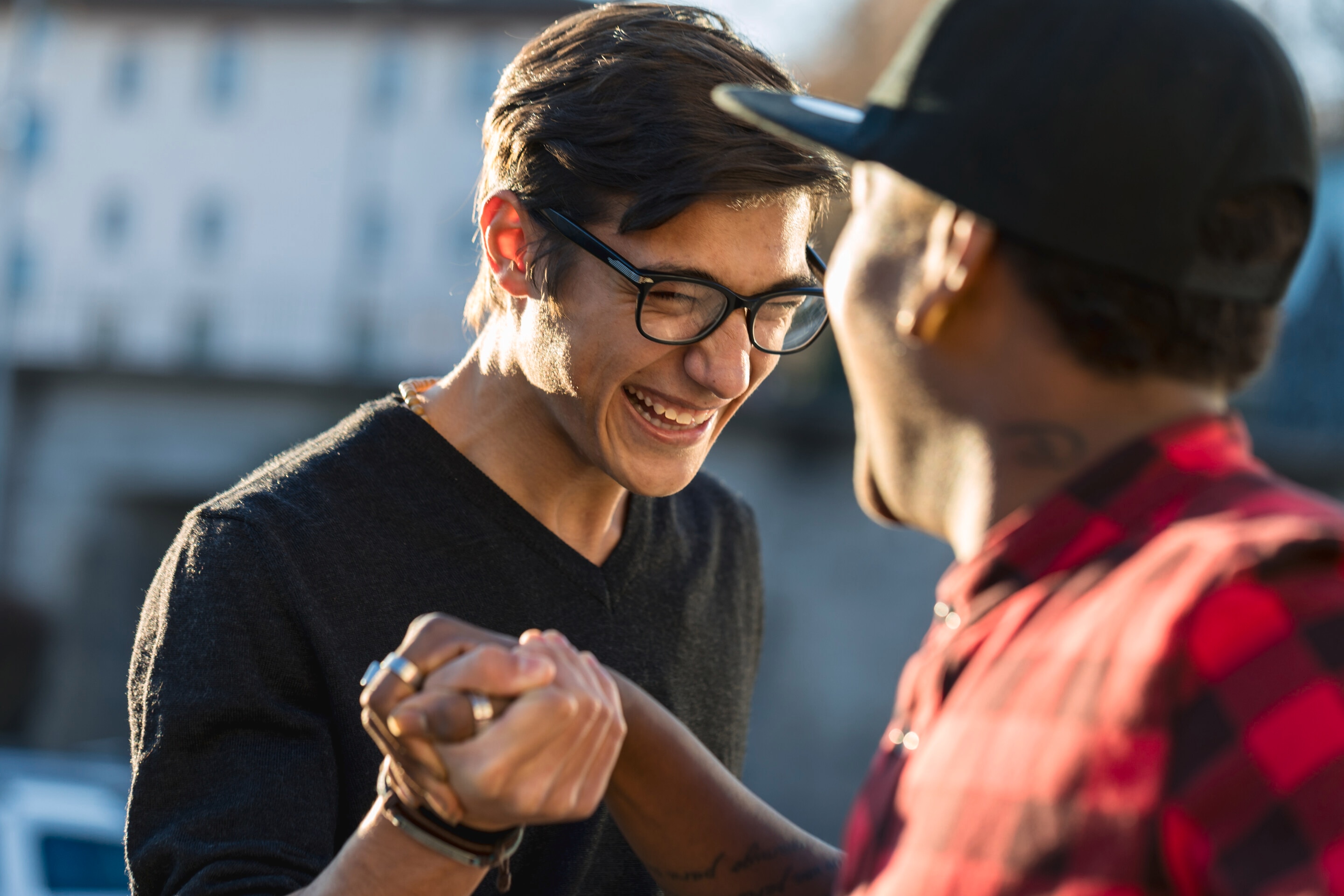 Two guys smiling and holding hands after a breakup