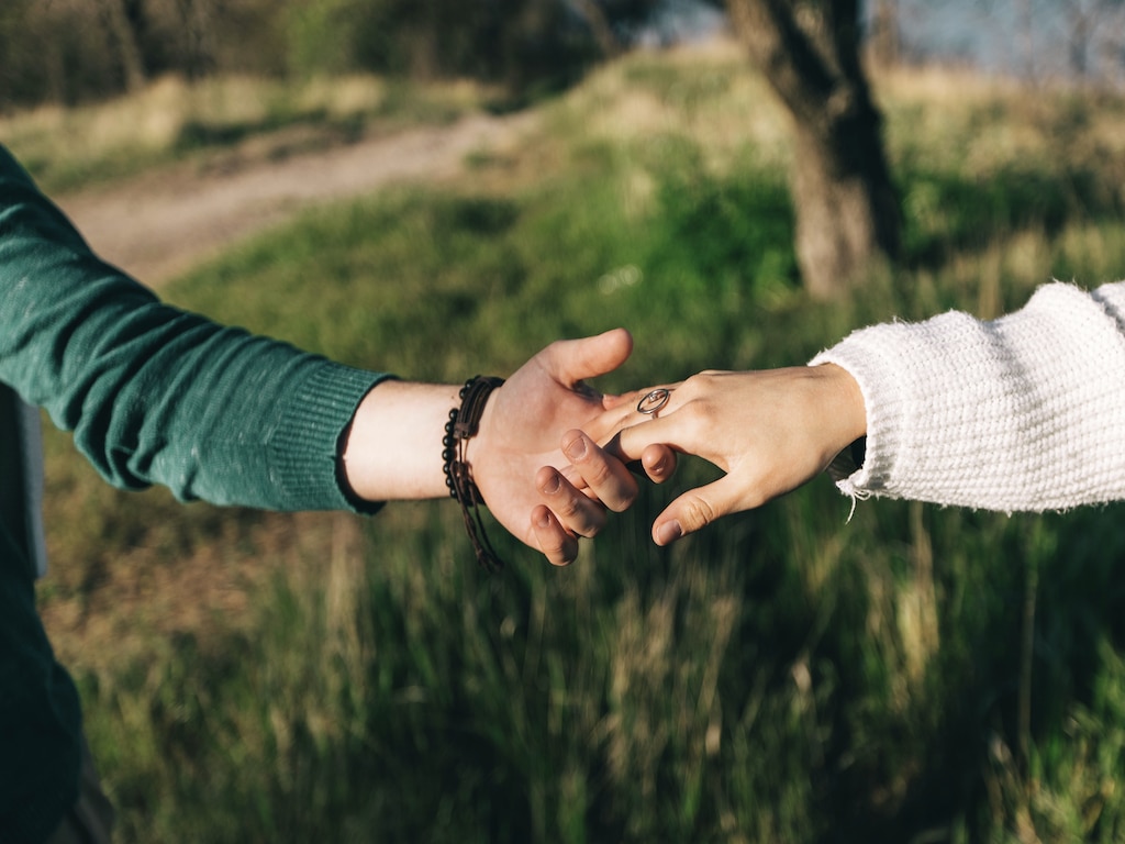 guy and girl holding hands outside in a field