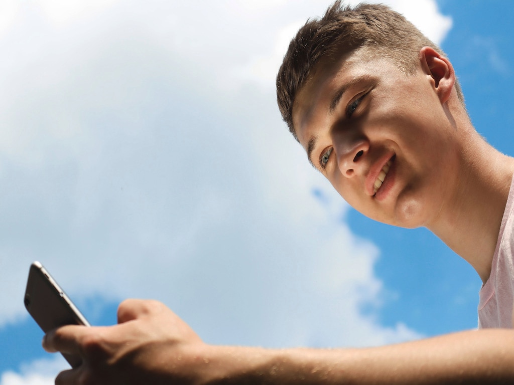 young guy smiling while looking at his phone