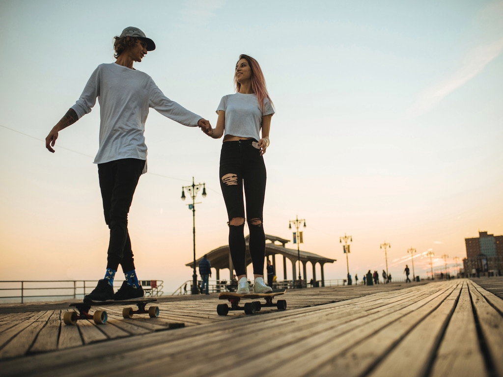 Girl and guy holding hands while on skateboard