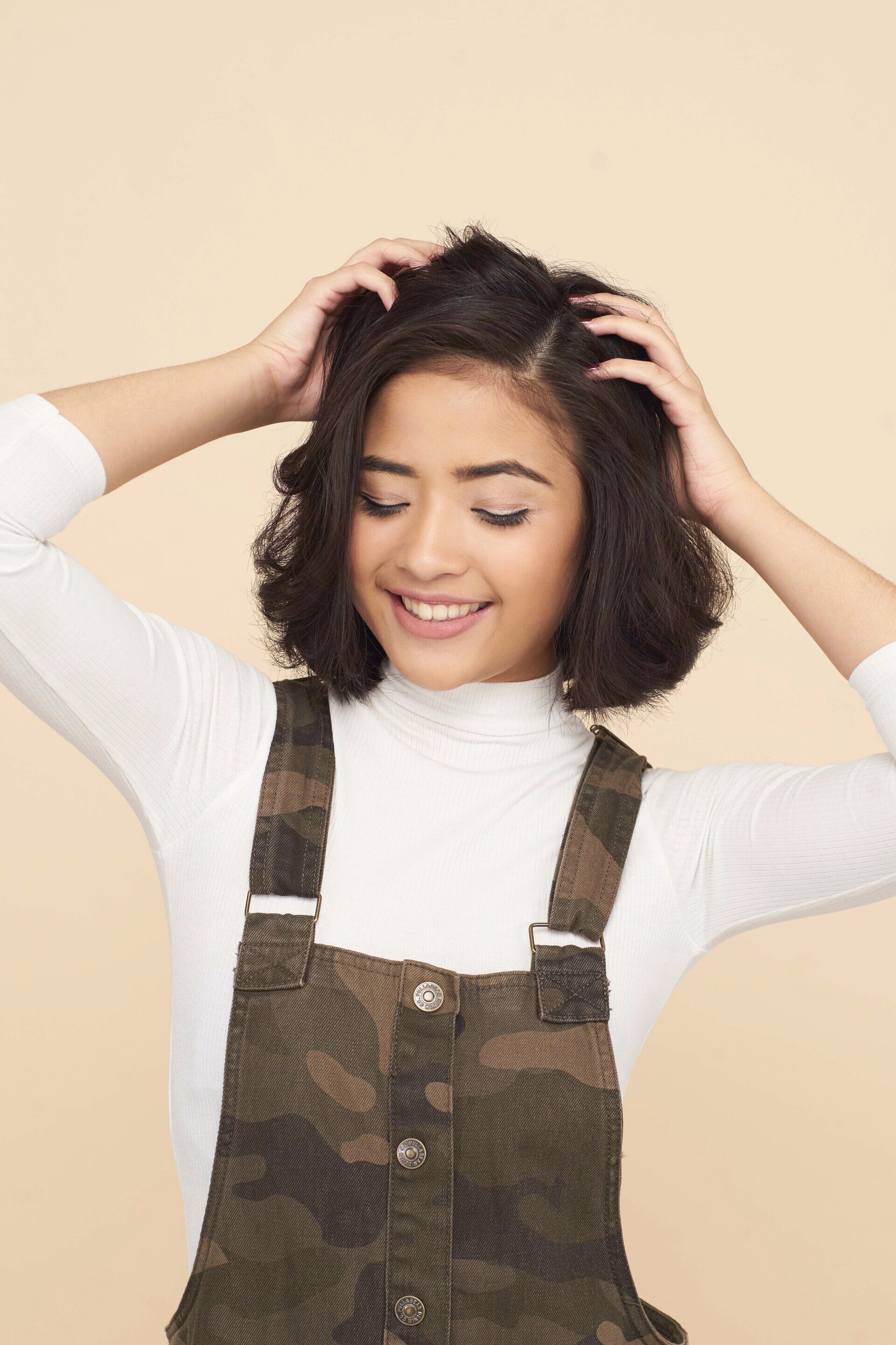 Wanita asia dengan rambut bob pendek warna hitam memegang kulit kepala