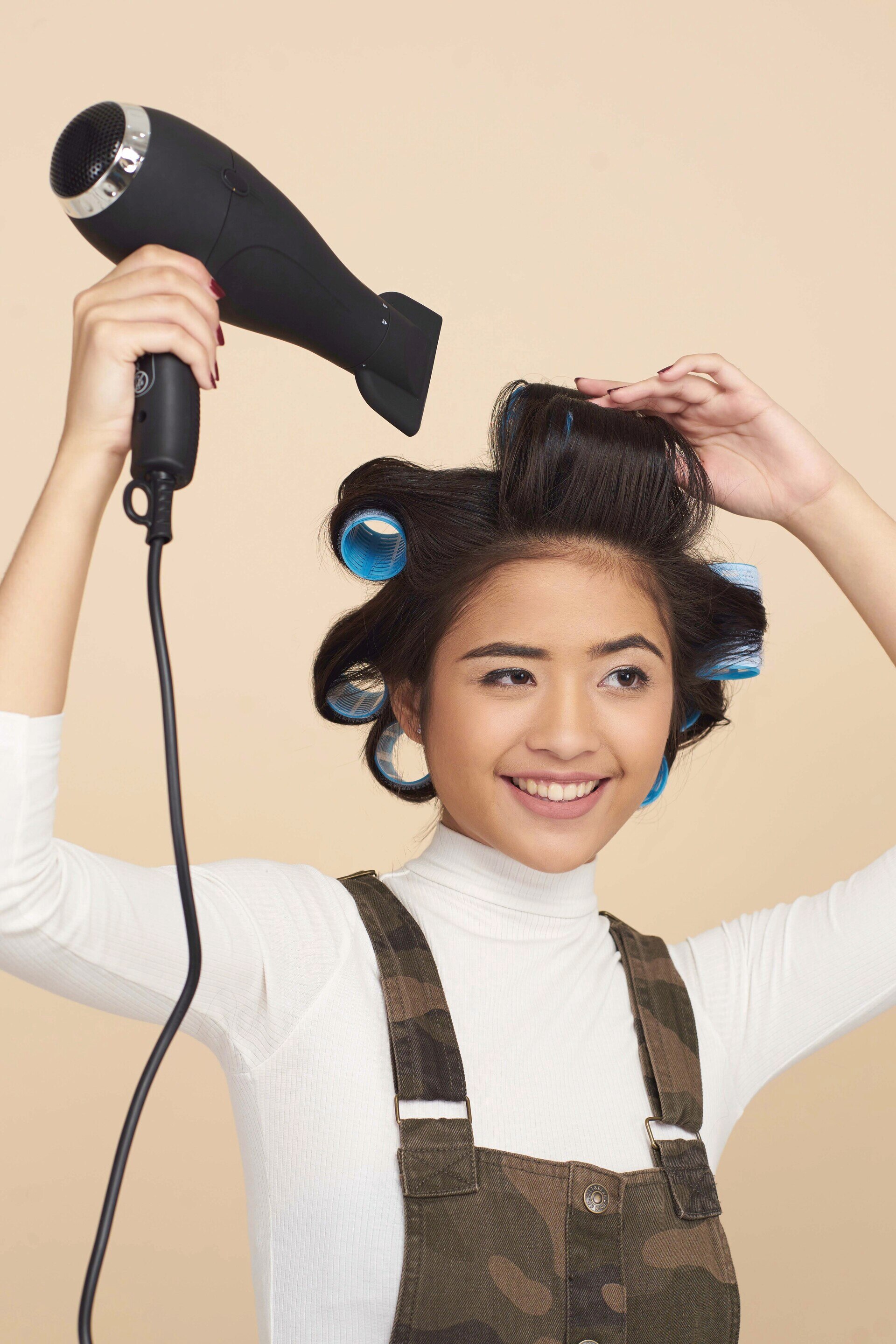 Wanita asia menunjukkan cara memakai rol rambut dengan hair dryer