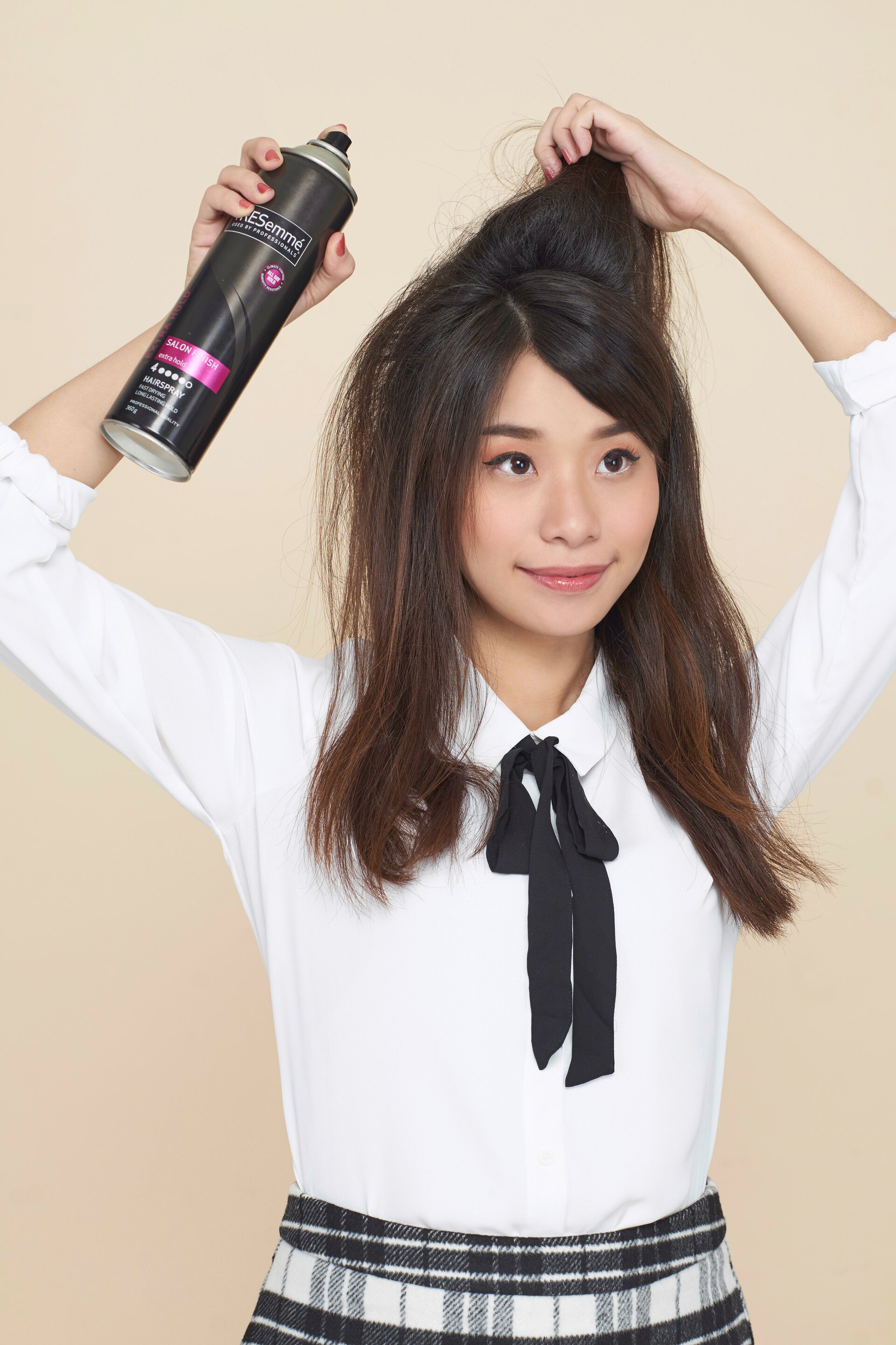 Wanita asia dengan rambut panjang menggunakan hairspray.
