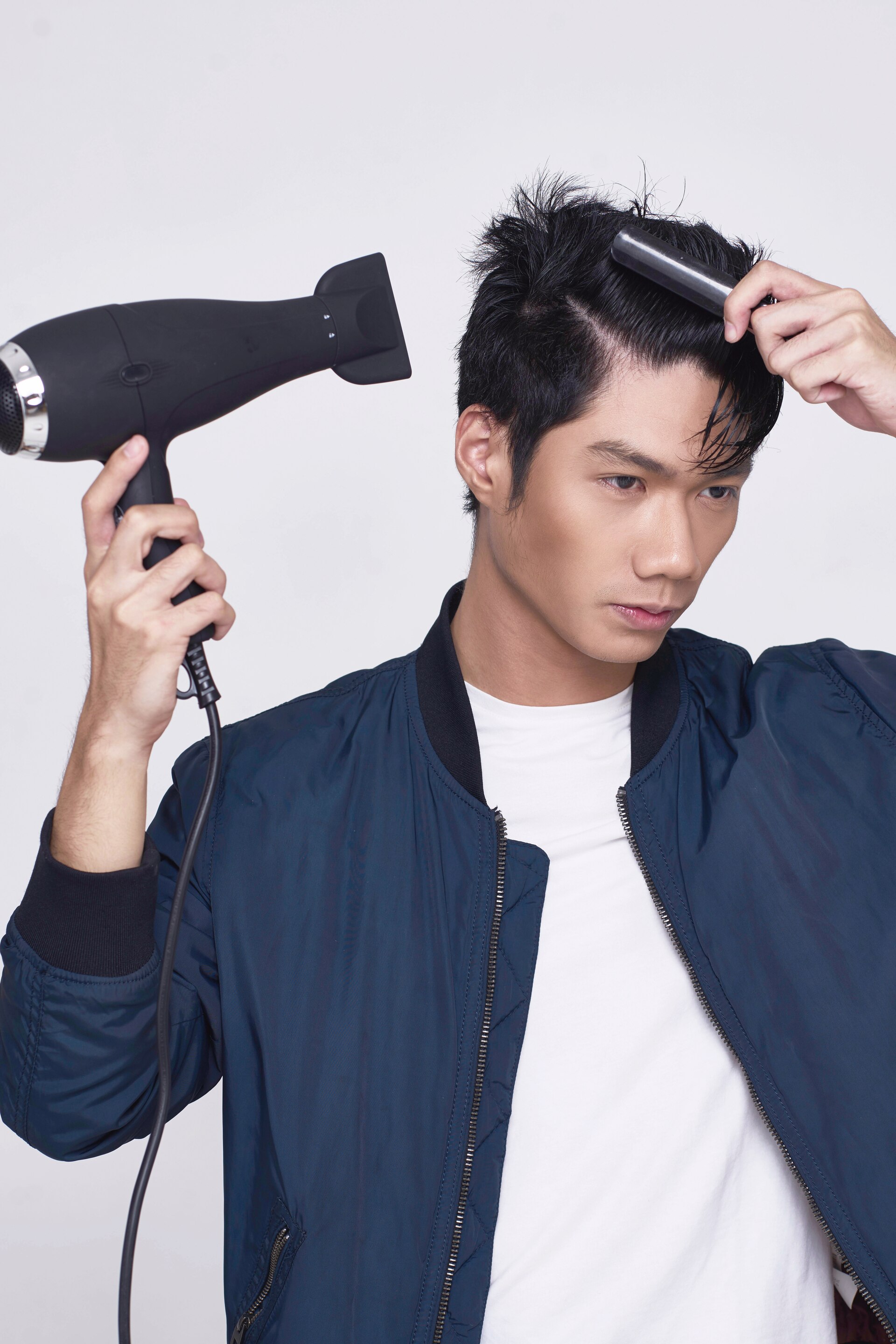 Pria asia dengan rambut pendek hitam menggunakan hairdryer – cara menata rambut pendek pria