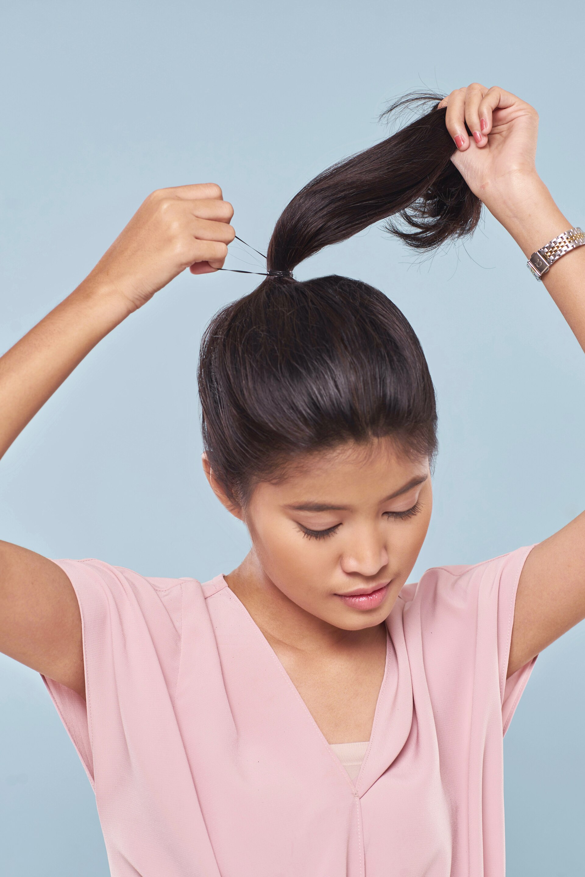 Wanita asia dengan warna rambut hitam mengikat rambut dengan ponytail.