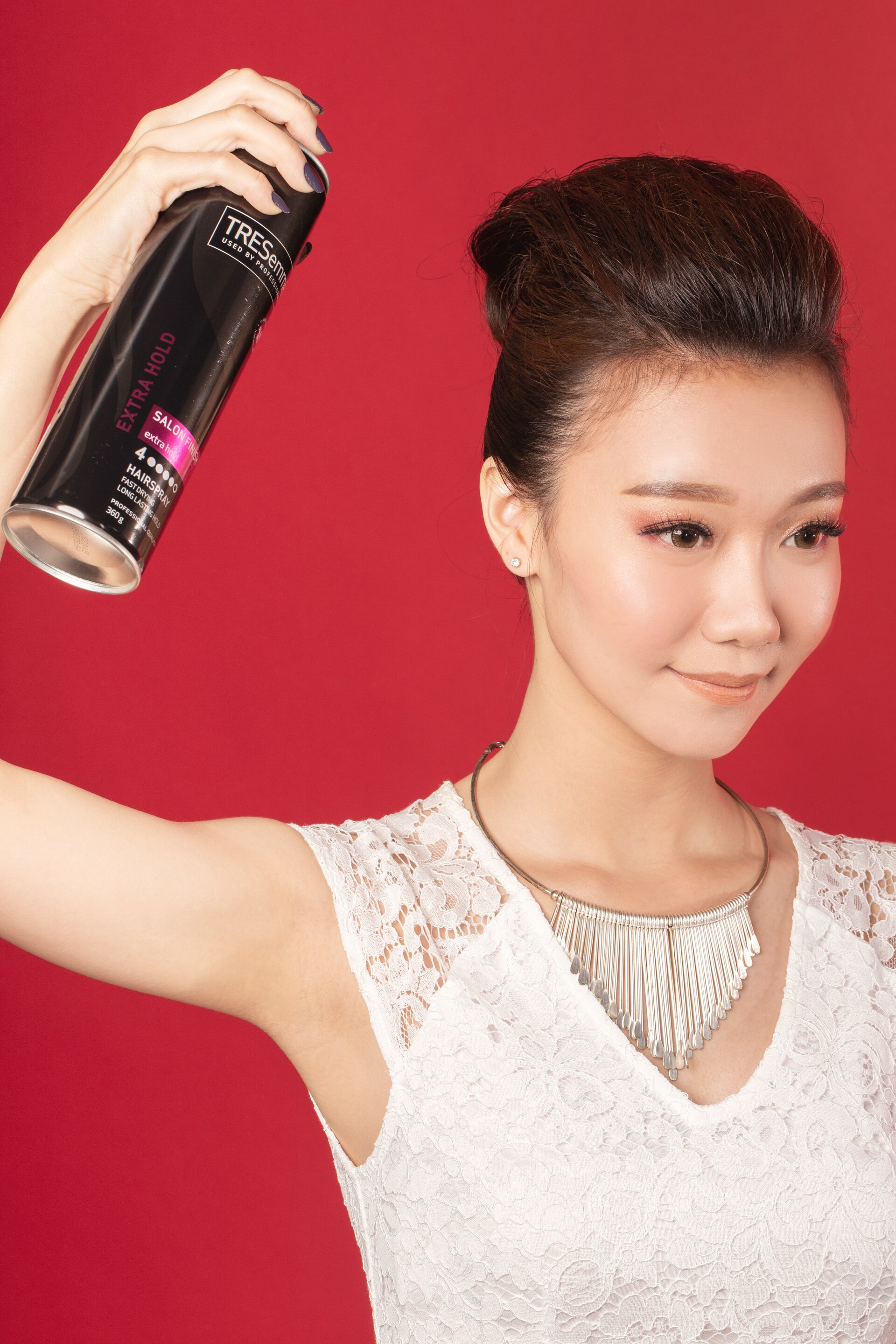 Wanita Asia menyemprotkan hairspray pada rambutnya