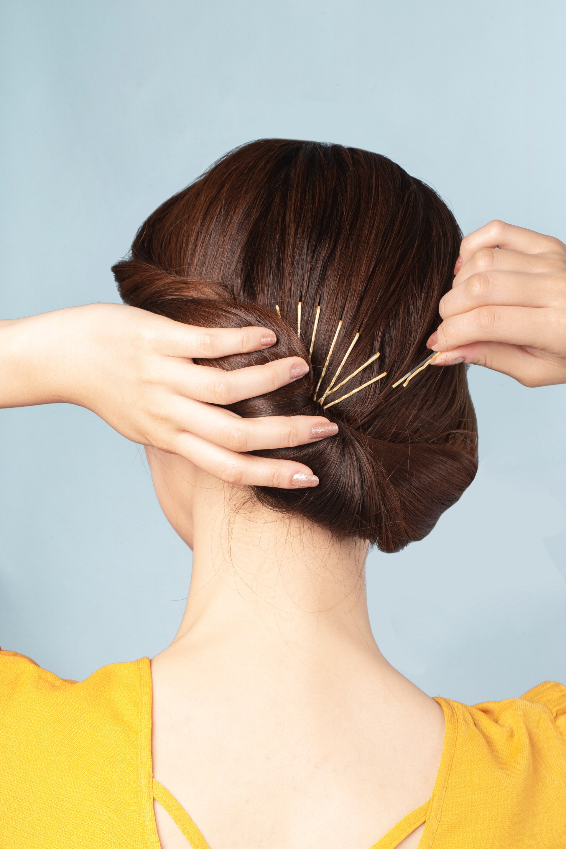 Wanita sedang menggunakan jepit rambut di rambut bagian belakang.