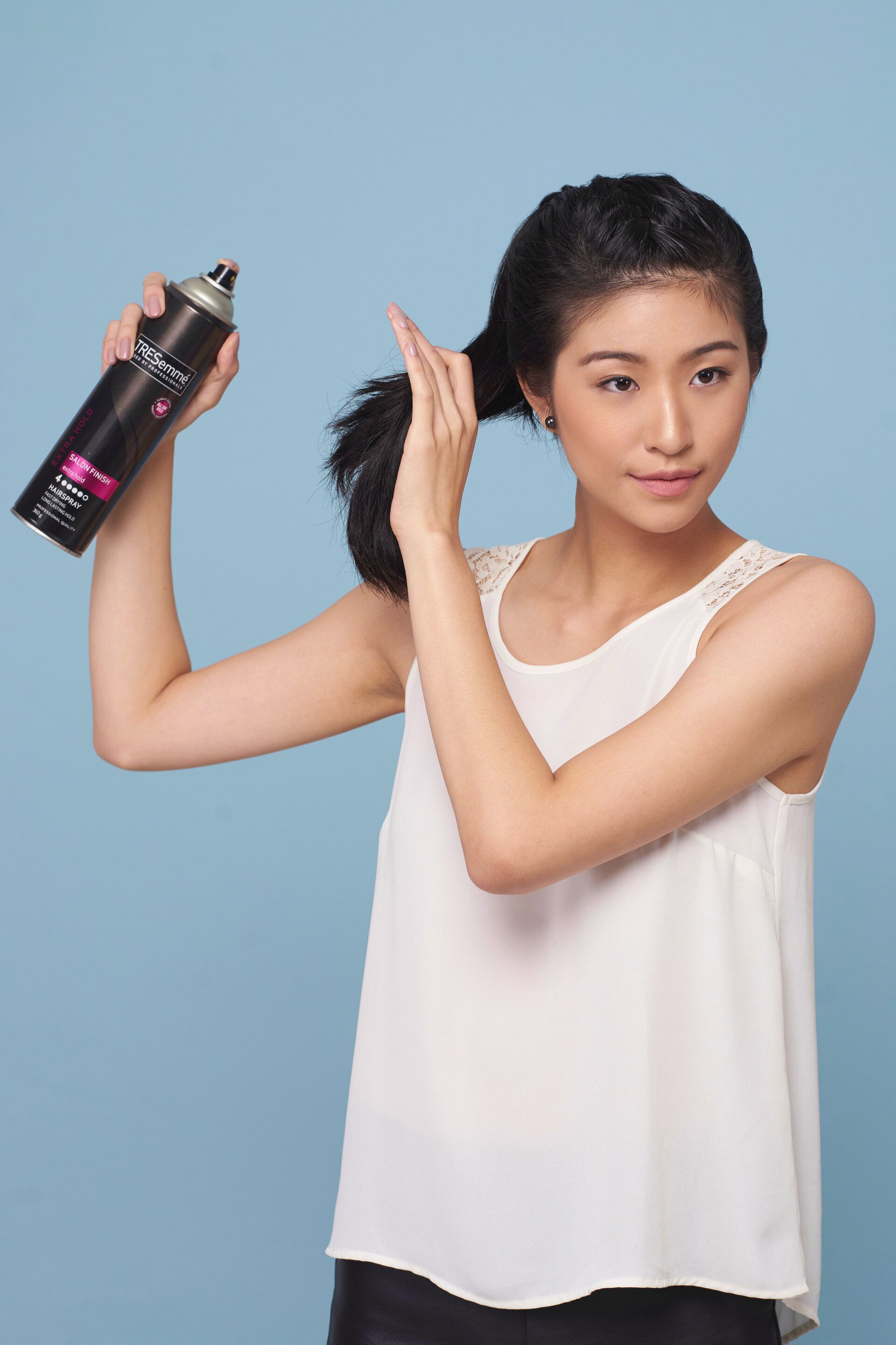 Wanita asia dengan gaya rambut french braid bun ponytail menyemprotkan hairspray