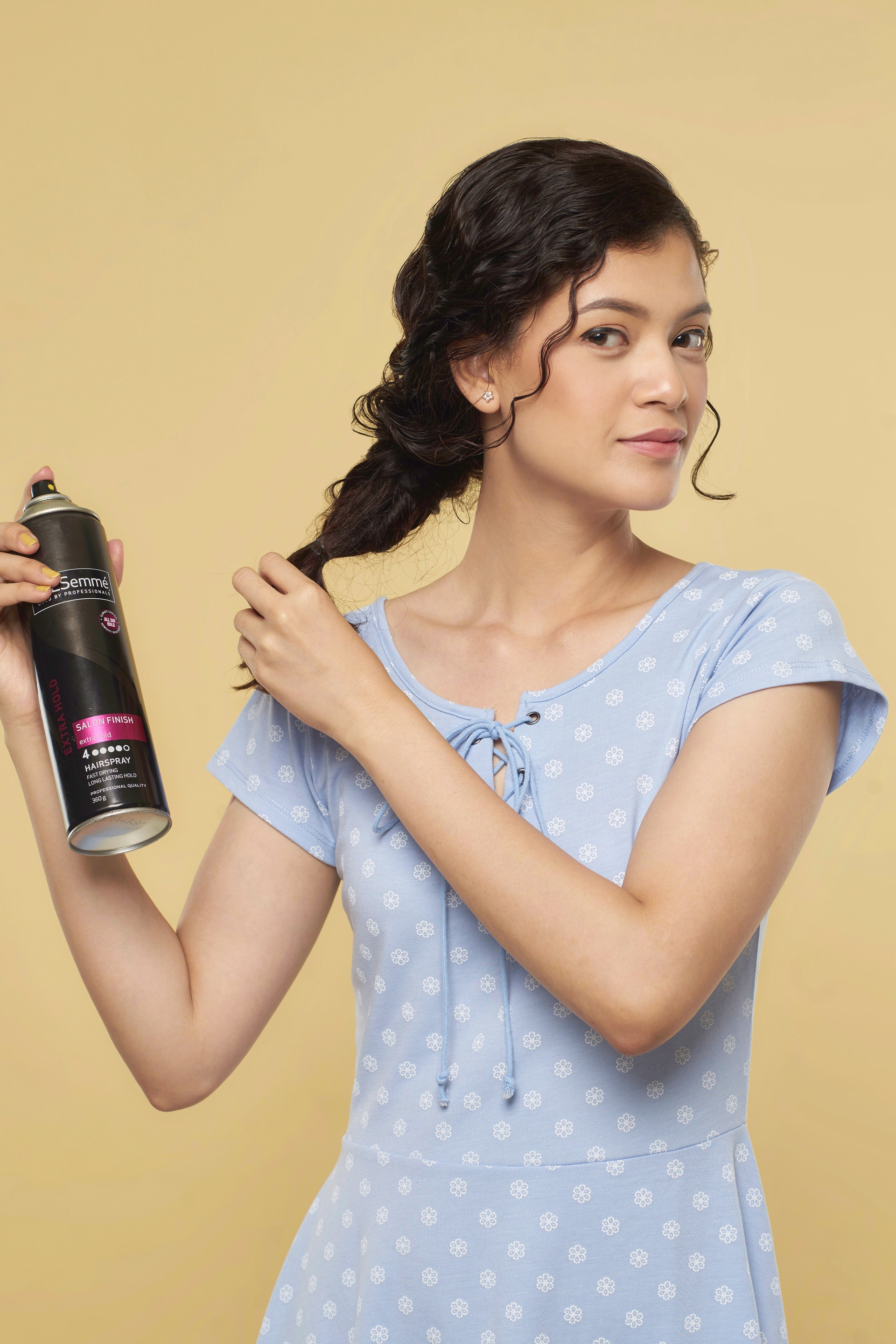 Wanita asia dnegan rambut keriting cokelat gaya mermaid braid menyemprotkan hairspray