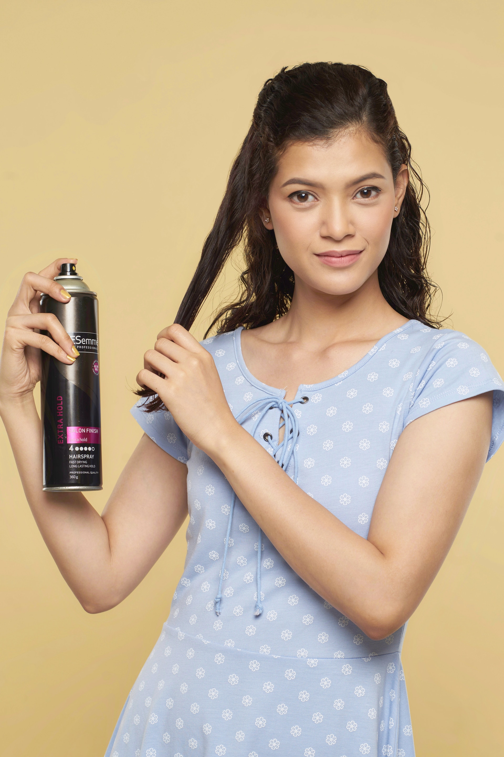 Wanita asia dengan rambut cokelat keriting gaya mermaid braid menyemprotkan hairspray