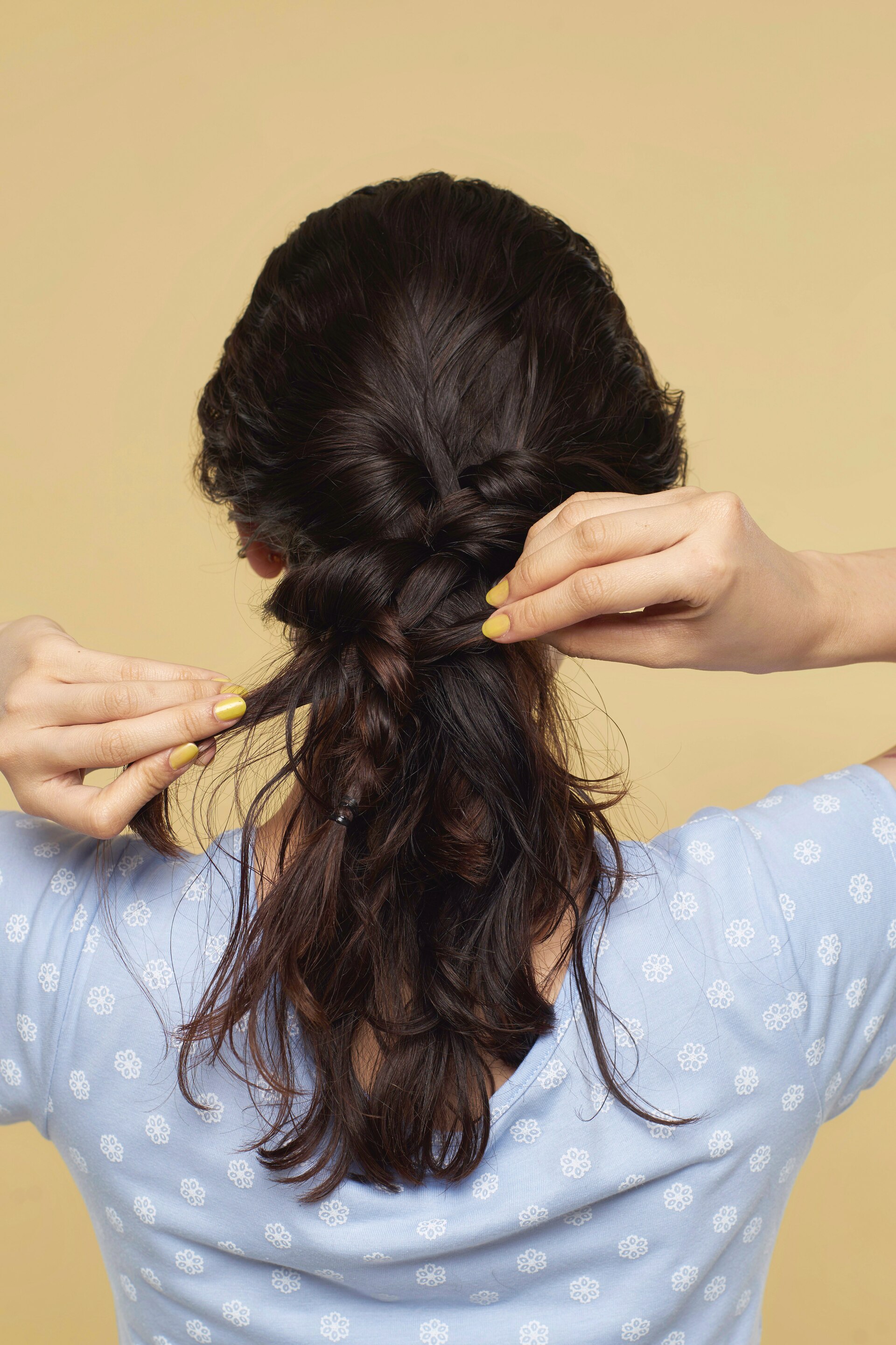 Wanita asia dengan model rambut mermaid braid membuat kepang di belakang kepala