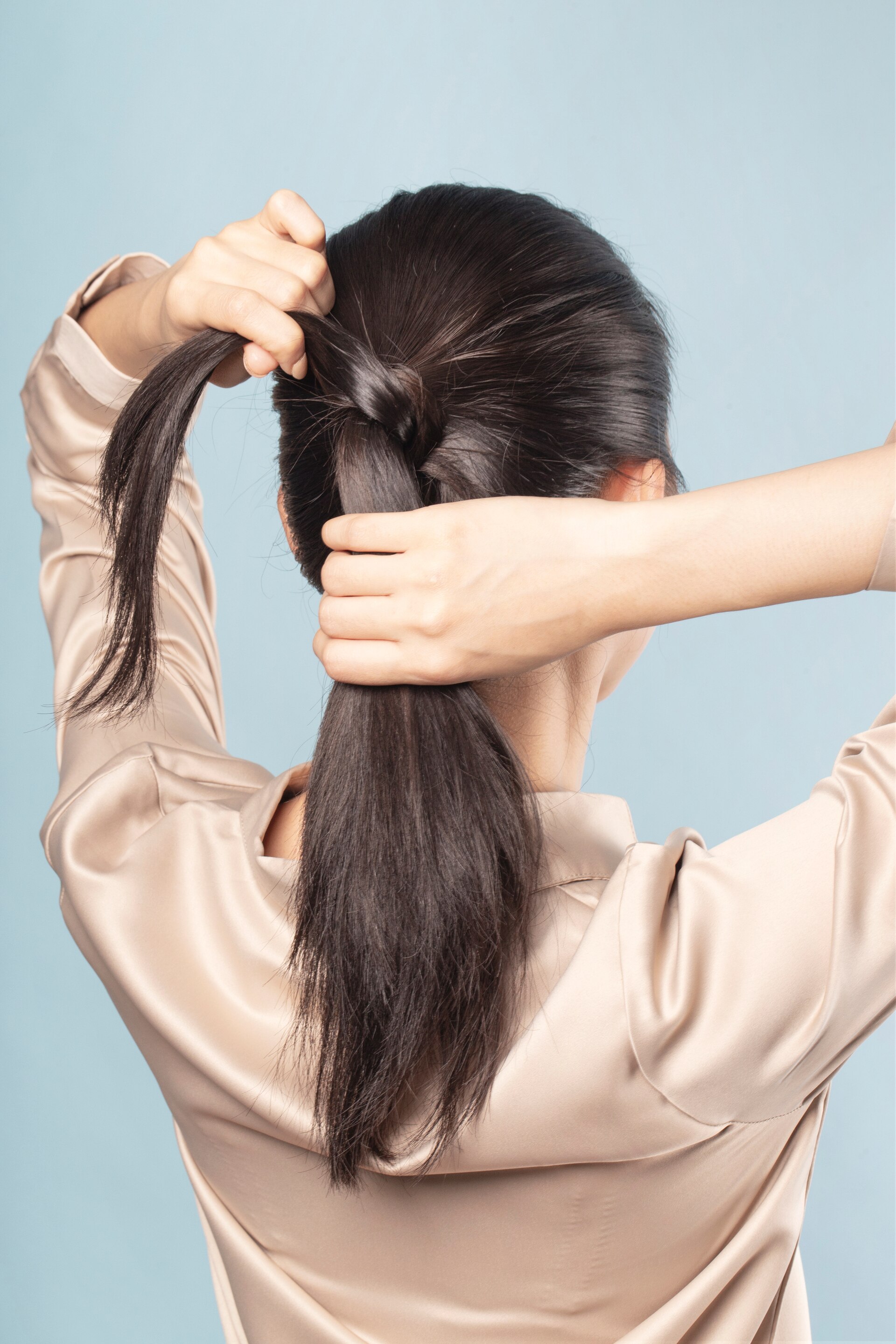 Wanita asia dengan rambut ponytail membuat half wrapped ponytail