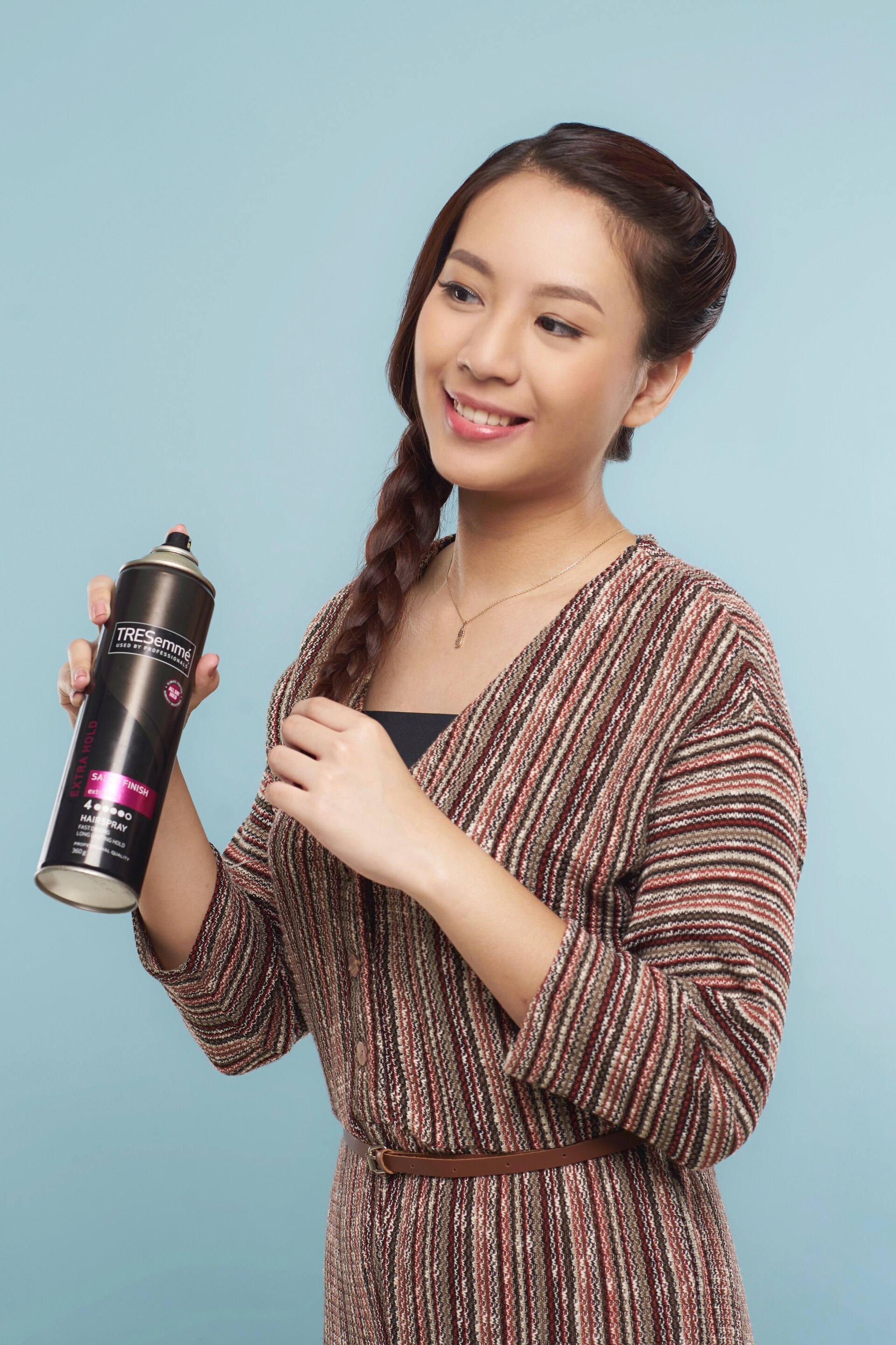 Wanita asia dengan rambut kepang menyemprotkan hairspray