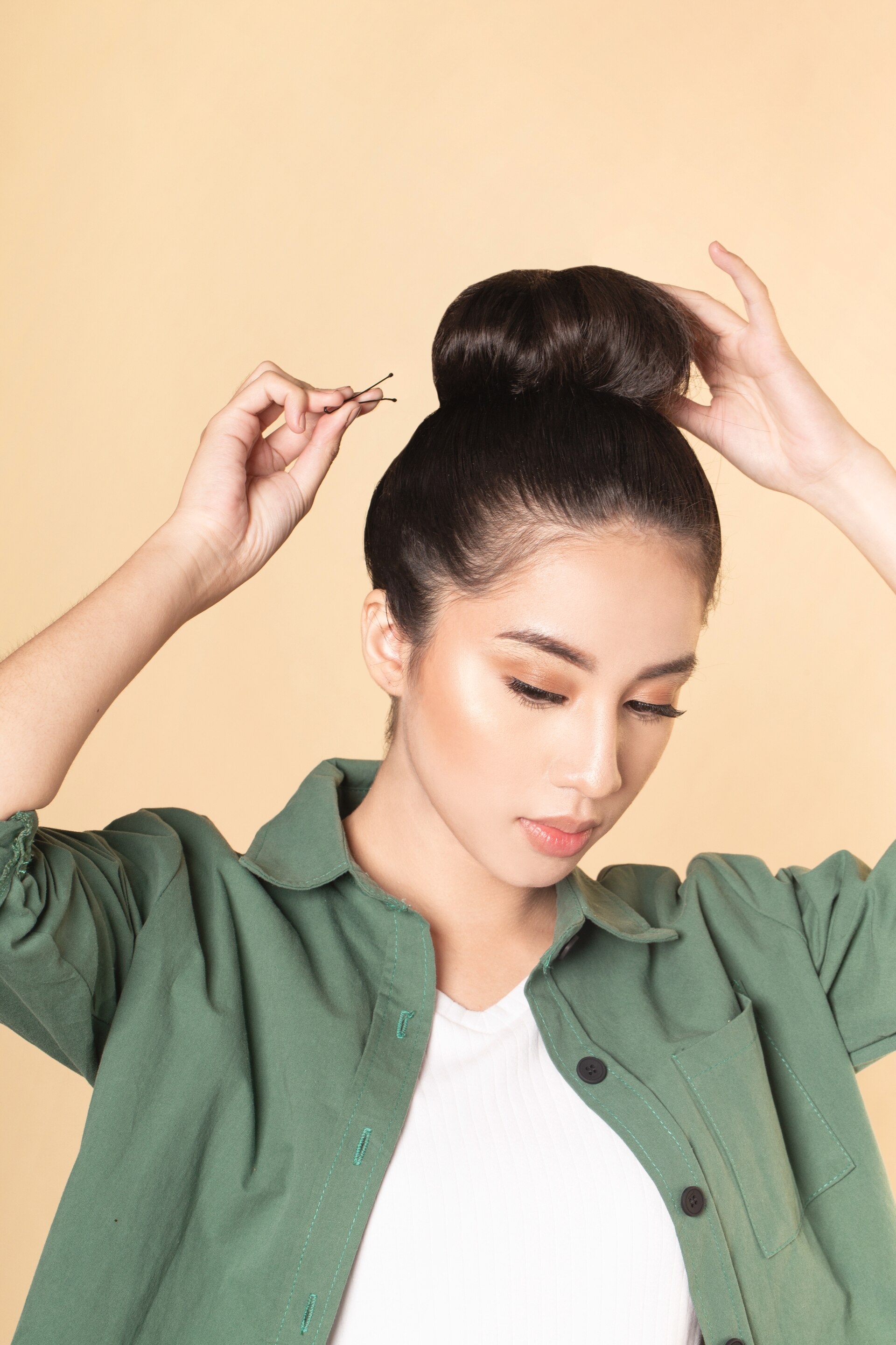 Wanita asia dengan rambut hitam memasang jepit para top knot
