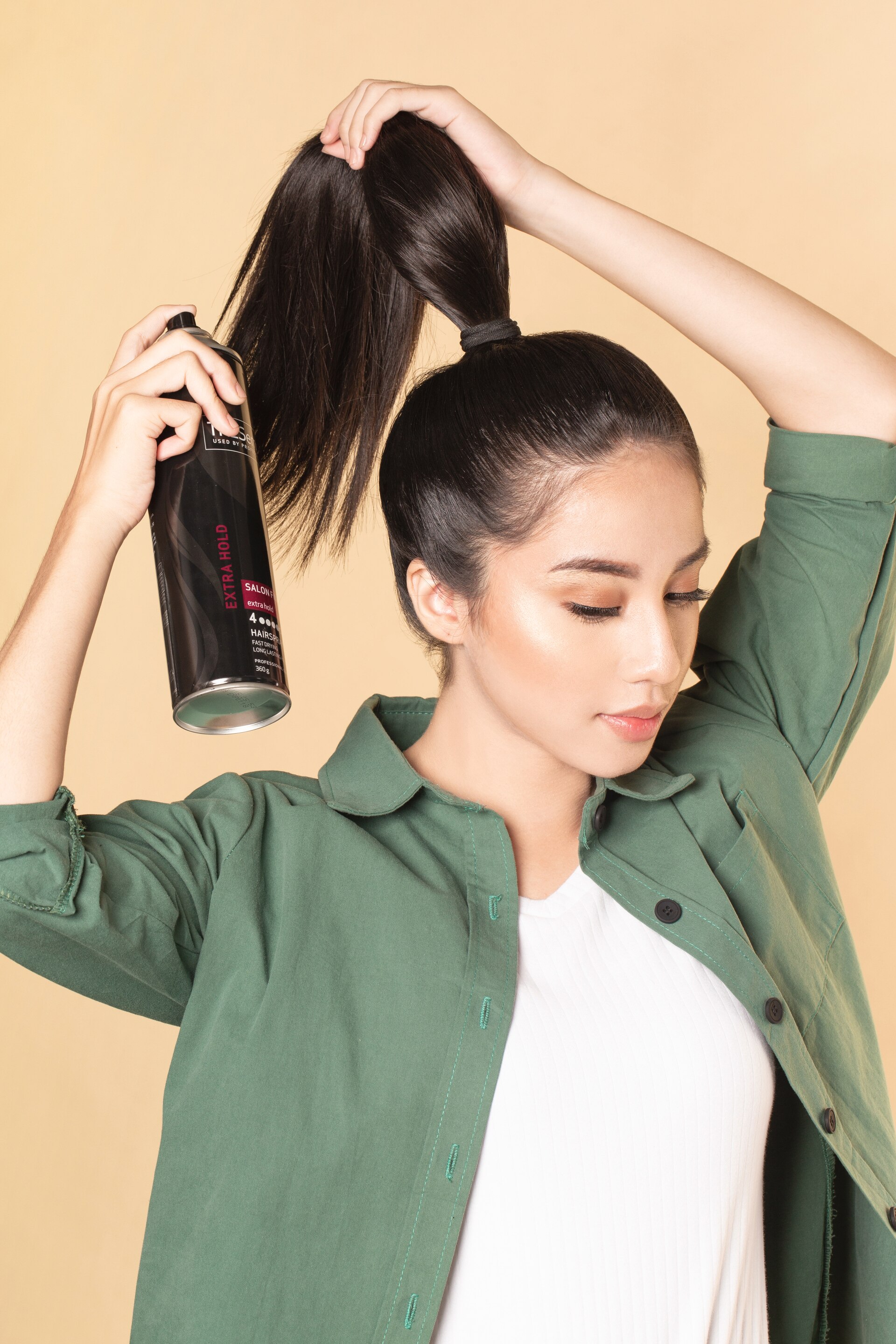 Wanita asia dengan rambut hitam menyemprotkan hairspray