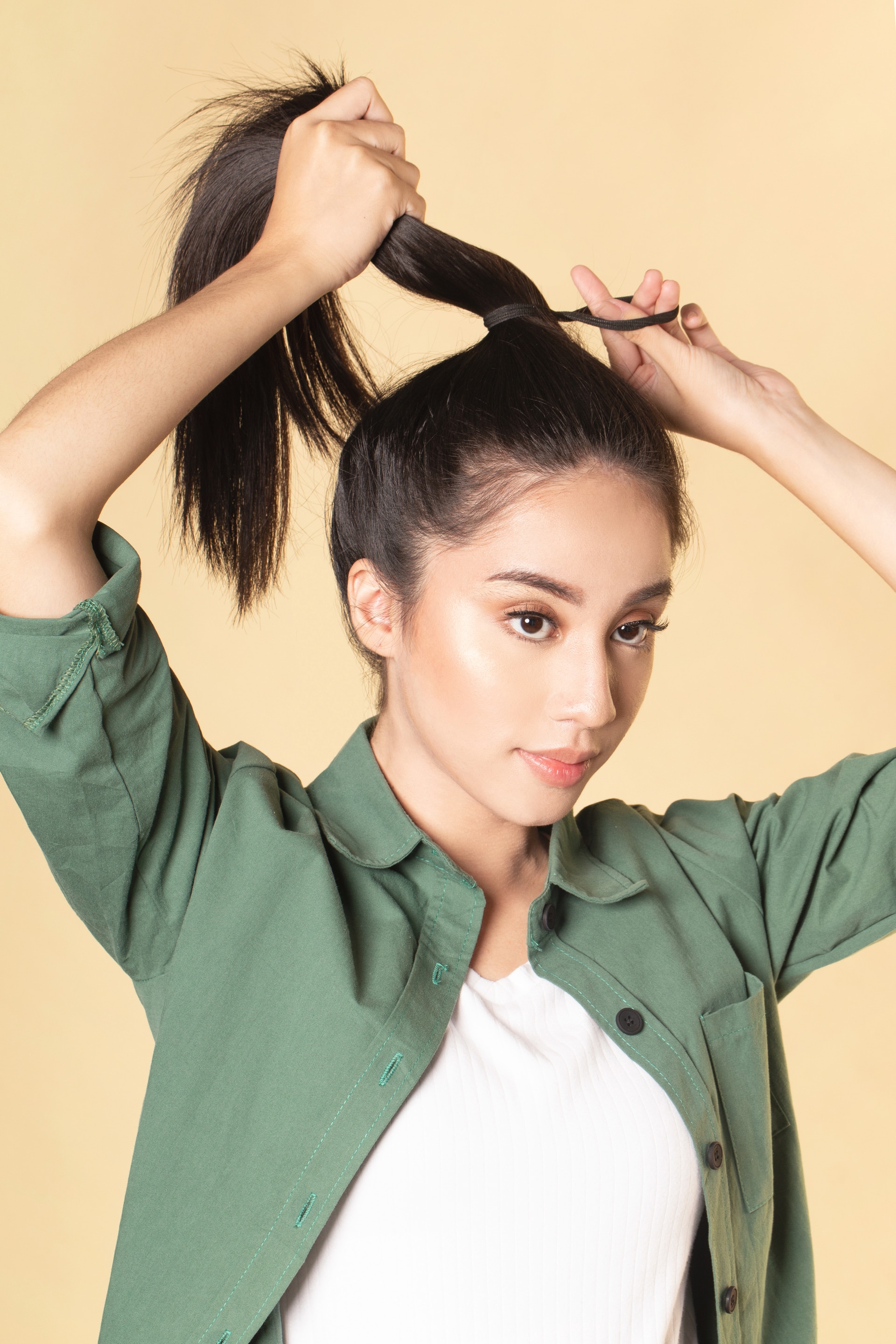 Wanita asia dengan rambut hitam membuat high ponytail