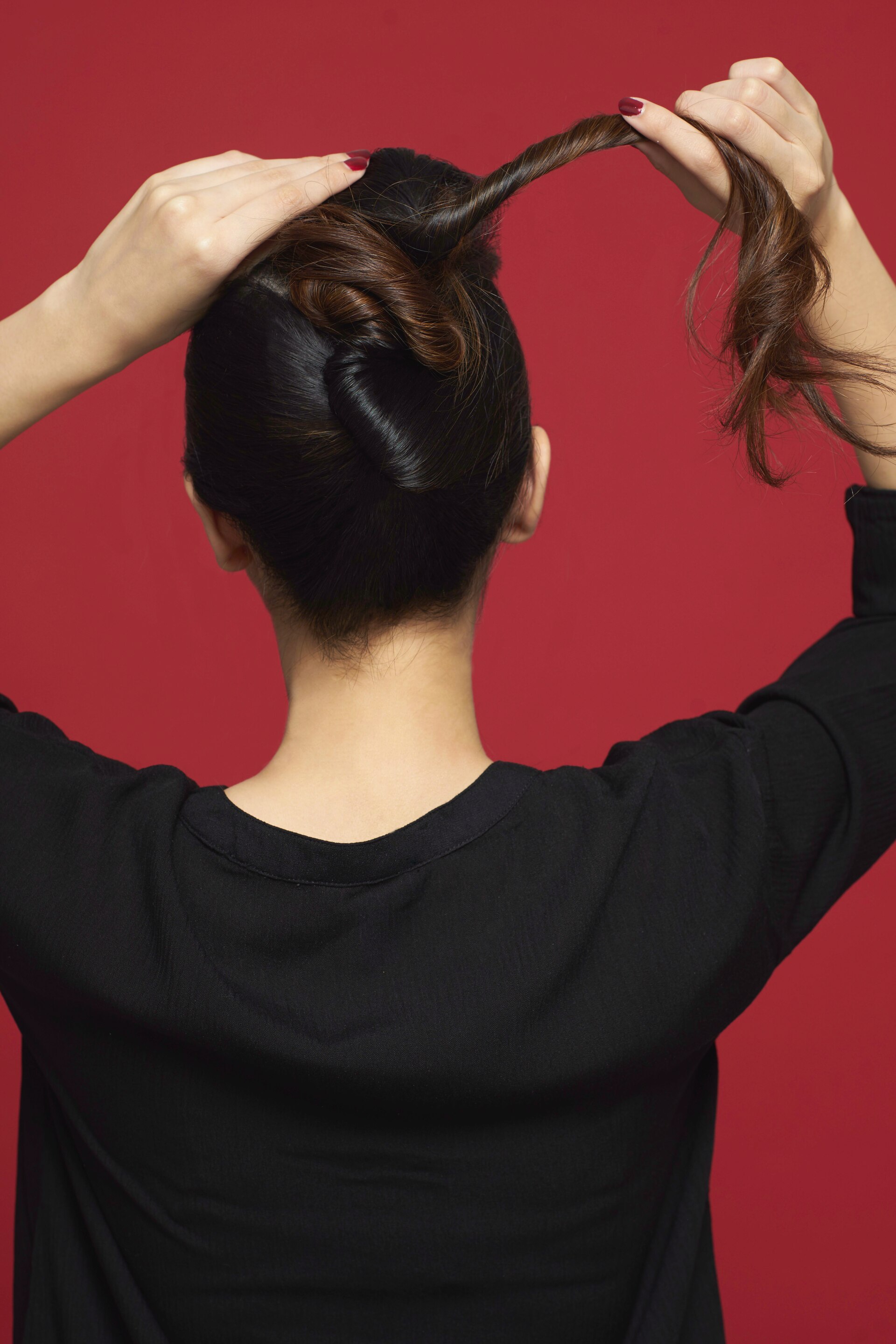 Wanita asia membuat twist pada bagian belakang rambut.